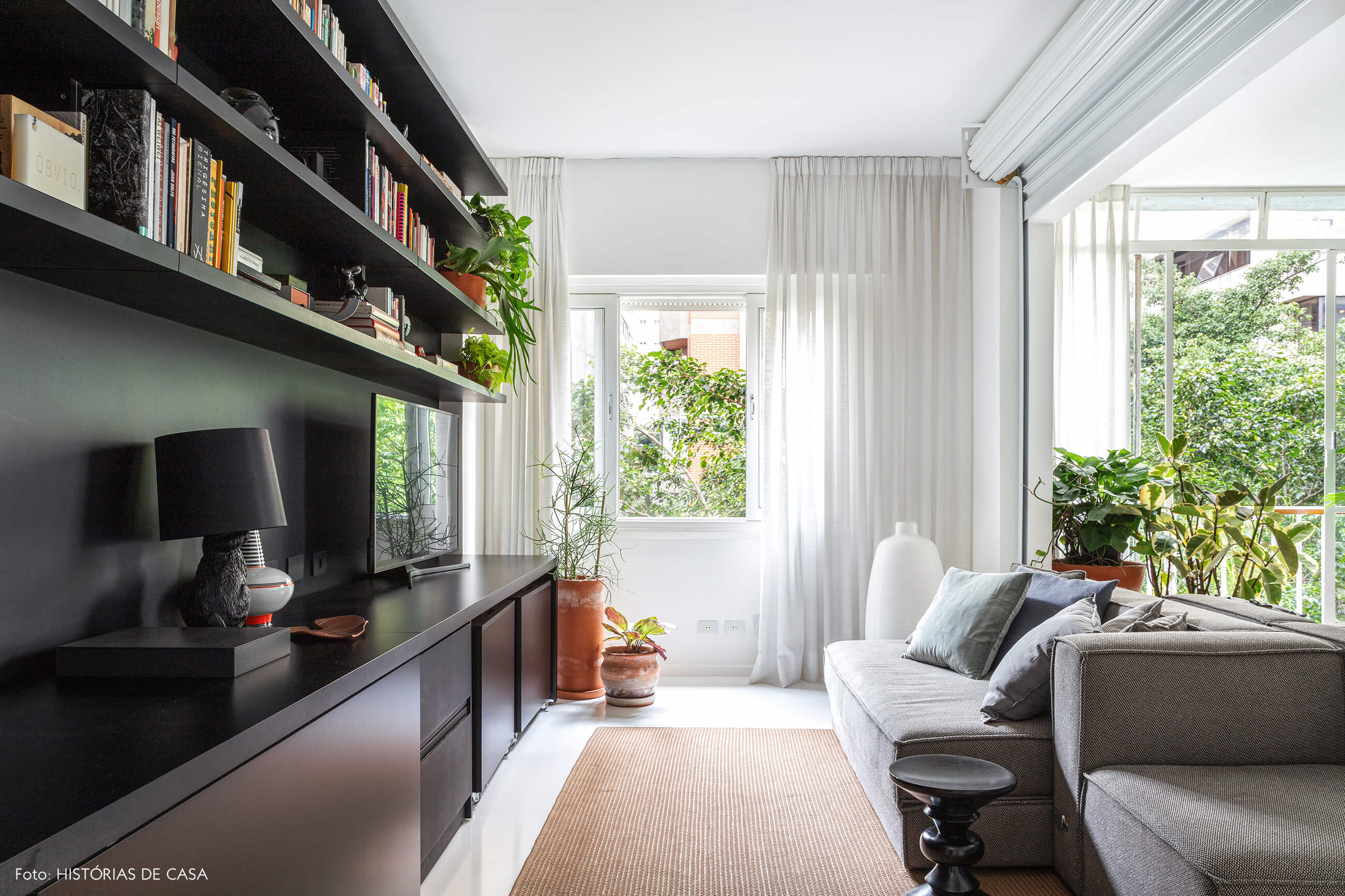 Apartamento escandinavo, sala com estante preta e sofá cinza