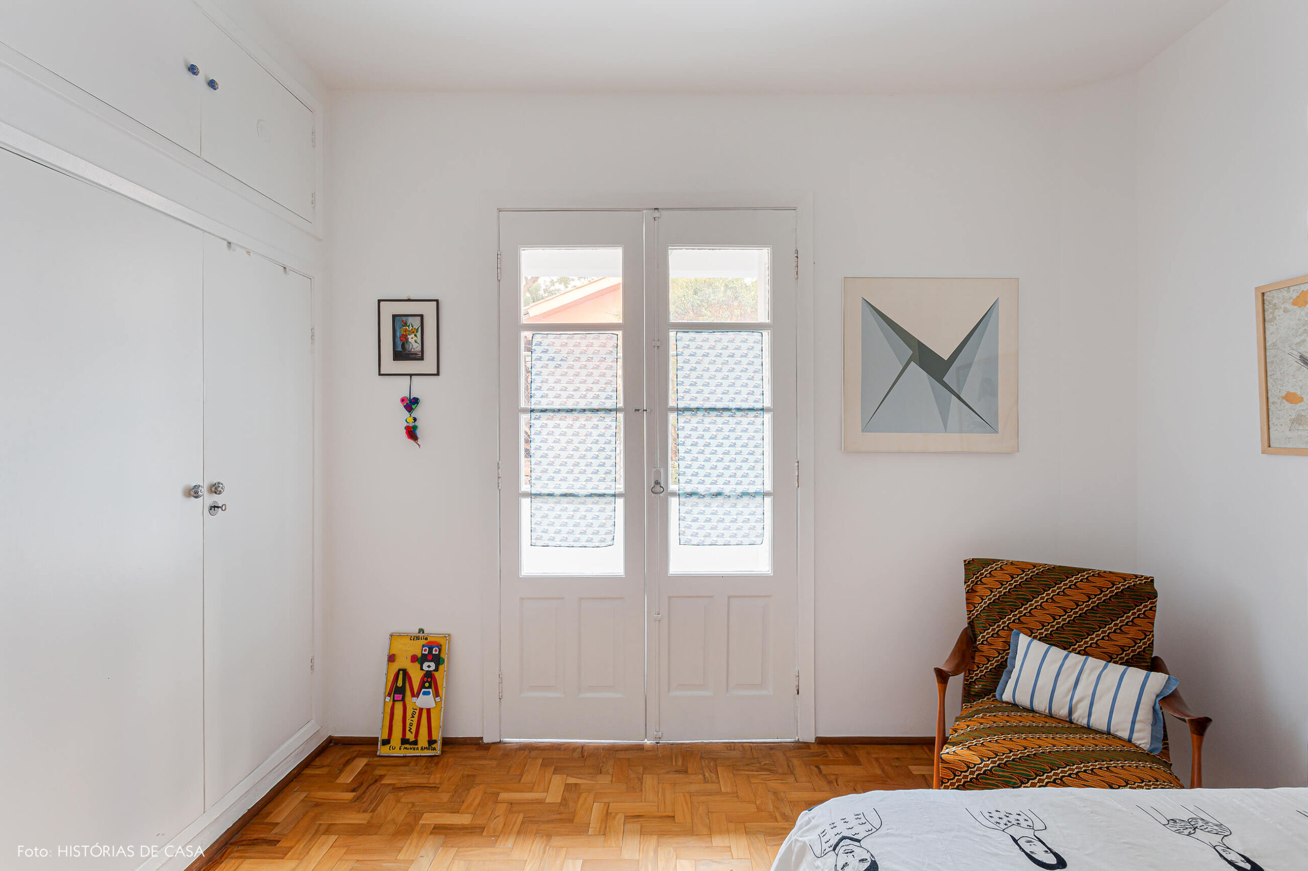 Quarto branco, parede de tijolos de vidro e portas de madeira