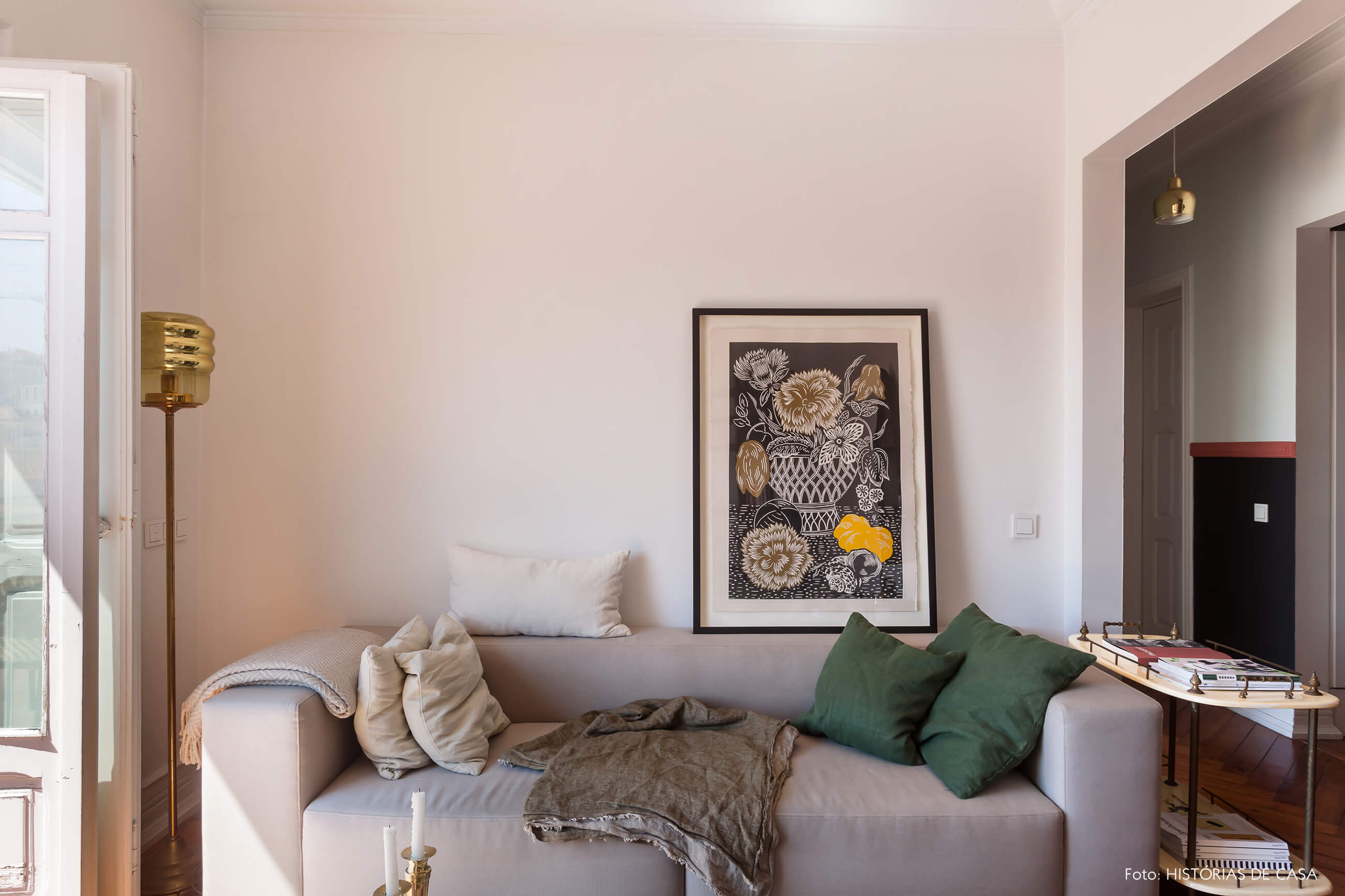 Decoração parede branca na sala e sofá cinza com quadro e almofadas verdes