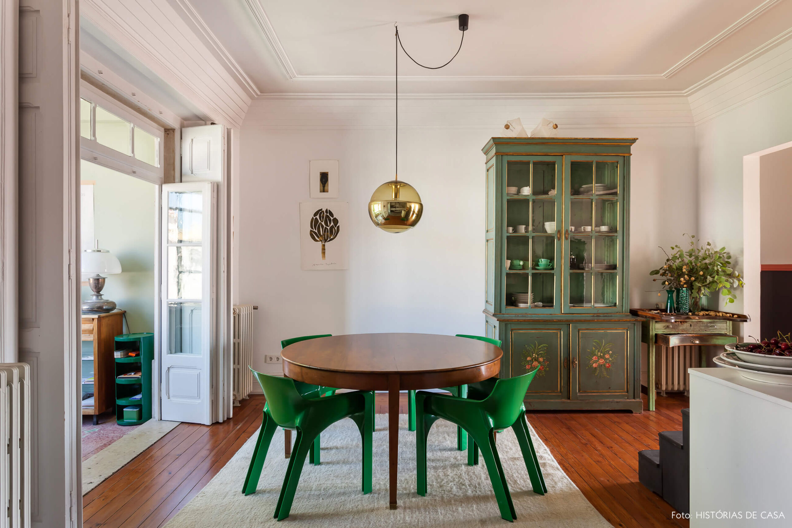 Decoração com cadeiras verdes e armário verde e luminária dourada