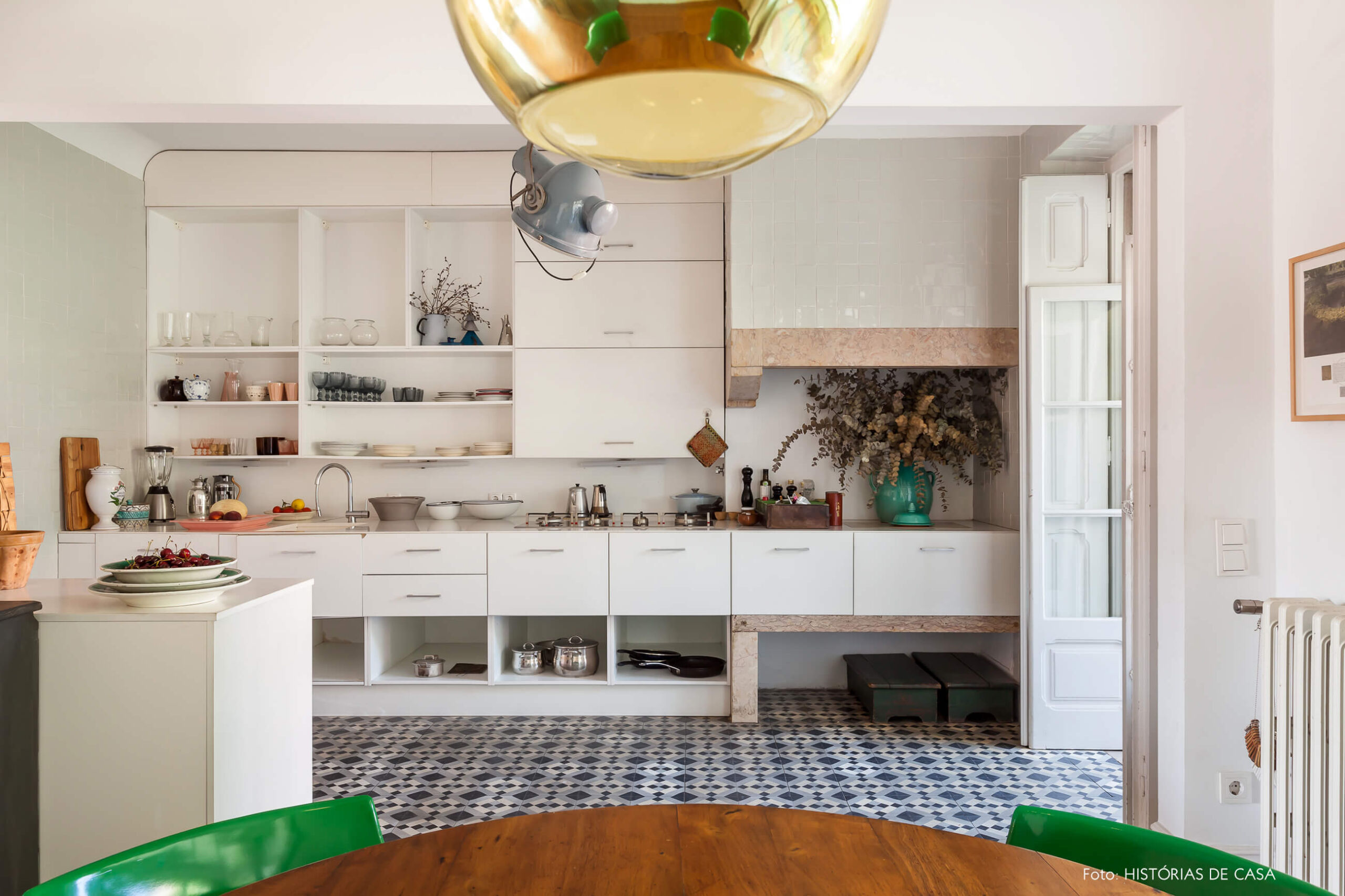 decoração da cozinha com caderias verdes luminária dourada e armários brancos