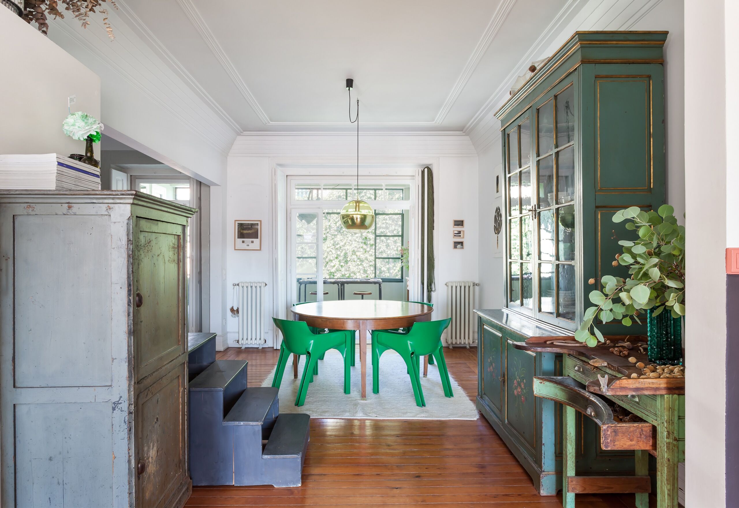 Sala decoração com piso de madeira e cadeiras e armários verdes