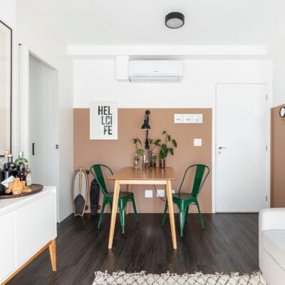 Sala com parede rosa bege e piso de madeira escura cadeiras verdes