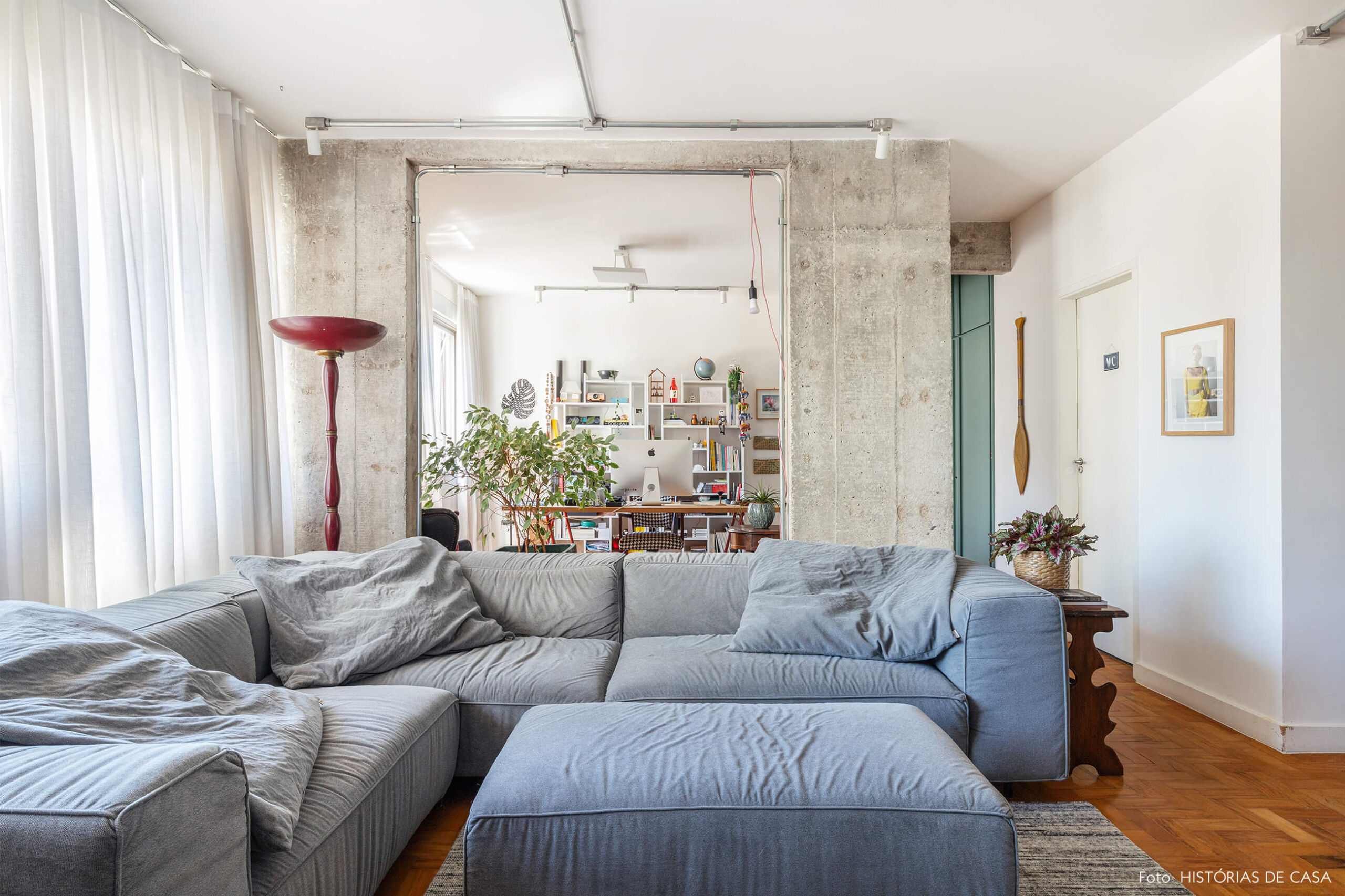 Sala com sofá azul e parede de concreto