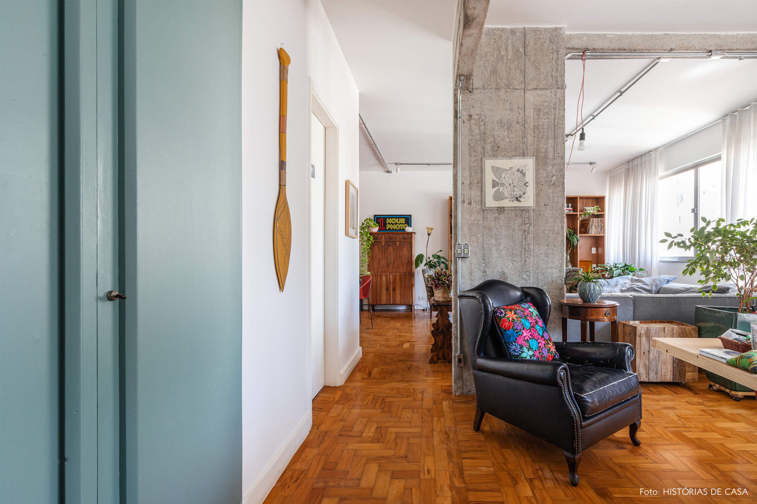 Sala com piso de madeira parede de concreto e poltrona de couro