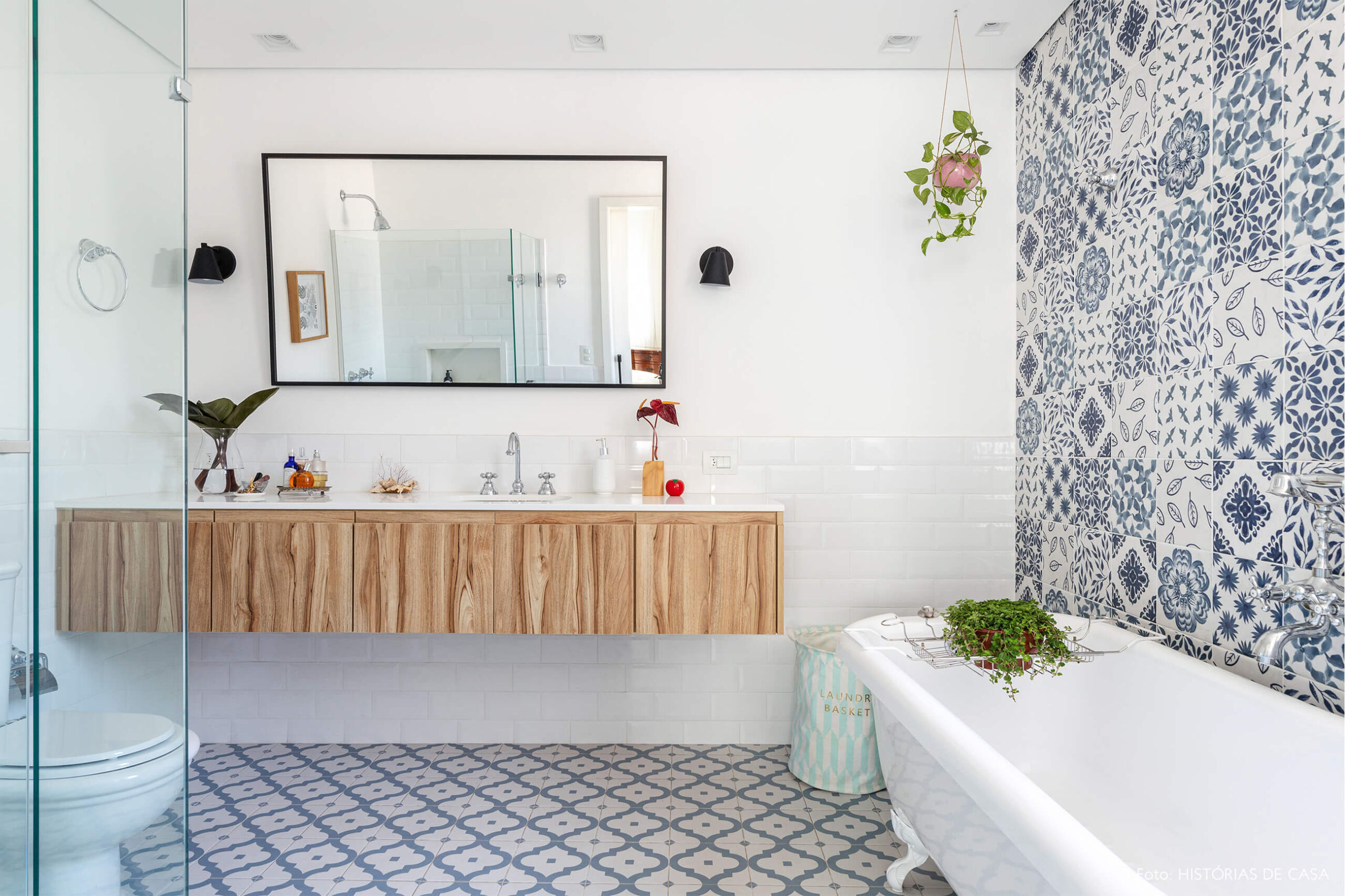 Banheiro com azulejo azul e branco e banheira e plantas