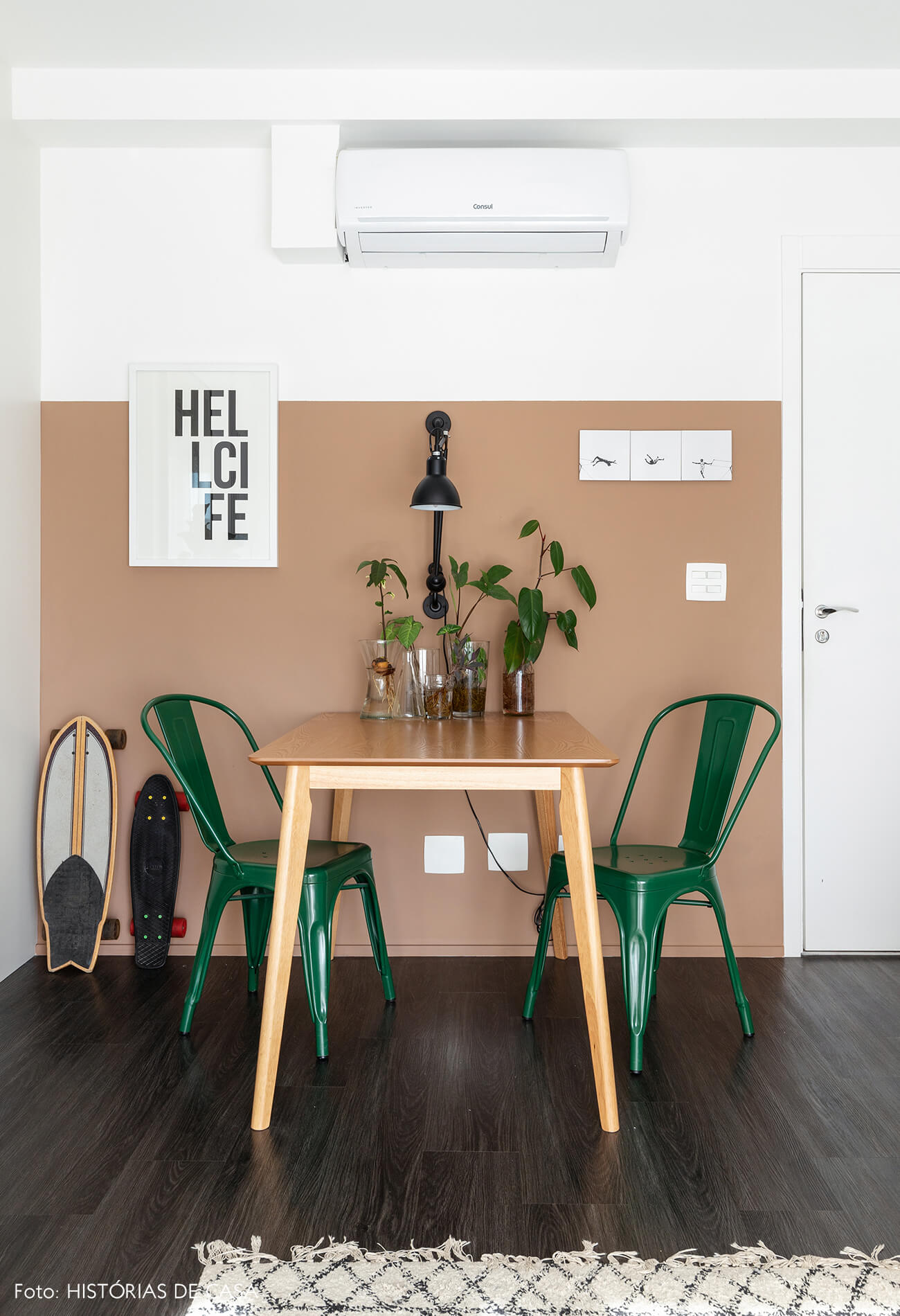 Sala com parede bege rosa e caderias verdes e piso de madeira