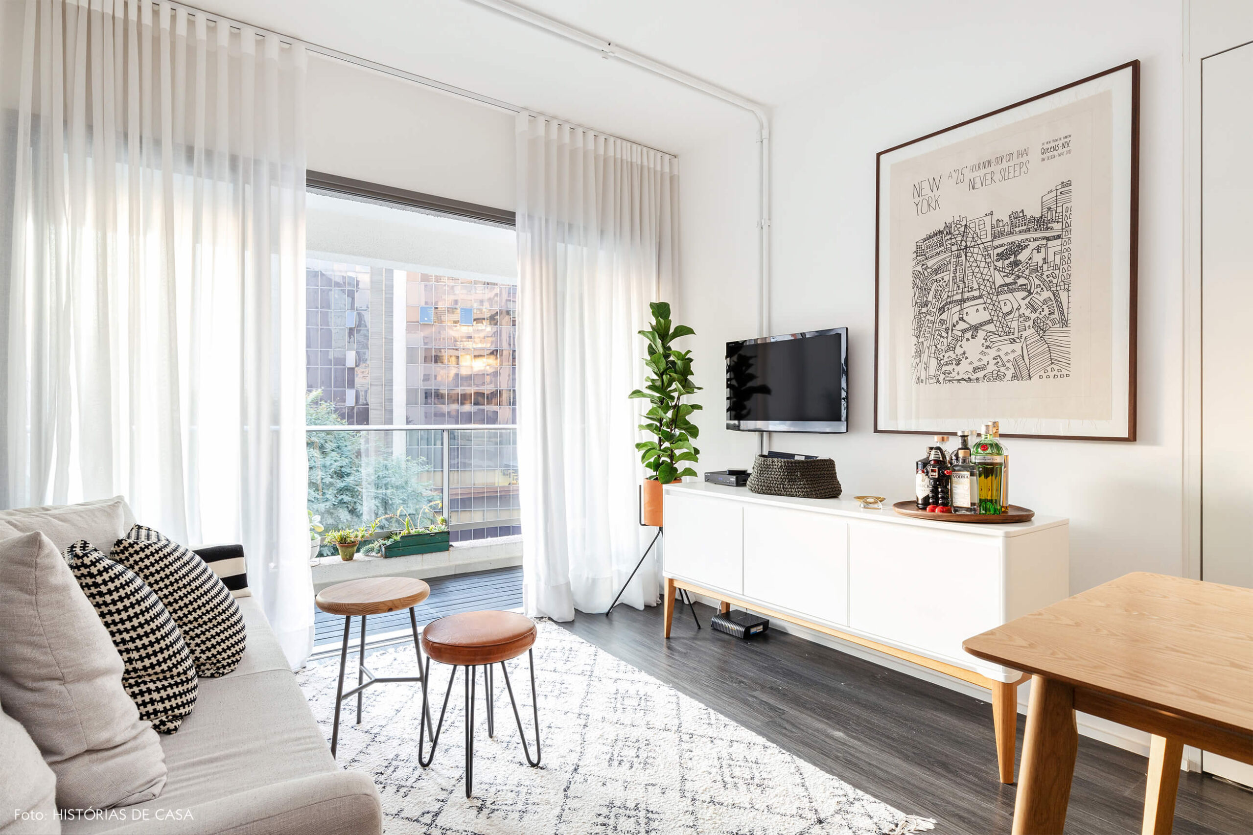 Sala com tapete branco e sofá cinza com quadro e planta