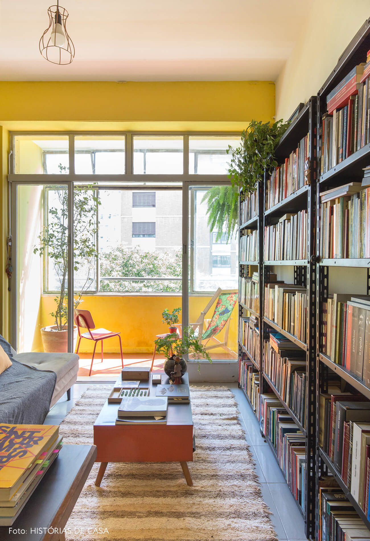 home-office-tapete-listrado-mesa-laranja-estante-preta-sofa-cinza-parede-amarela-e-roxa-varanda