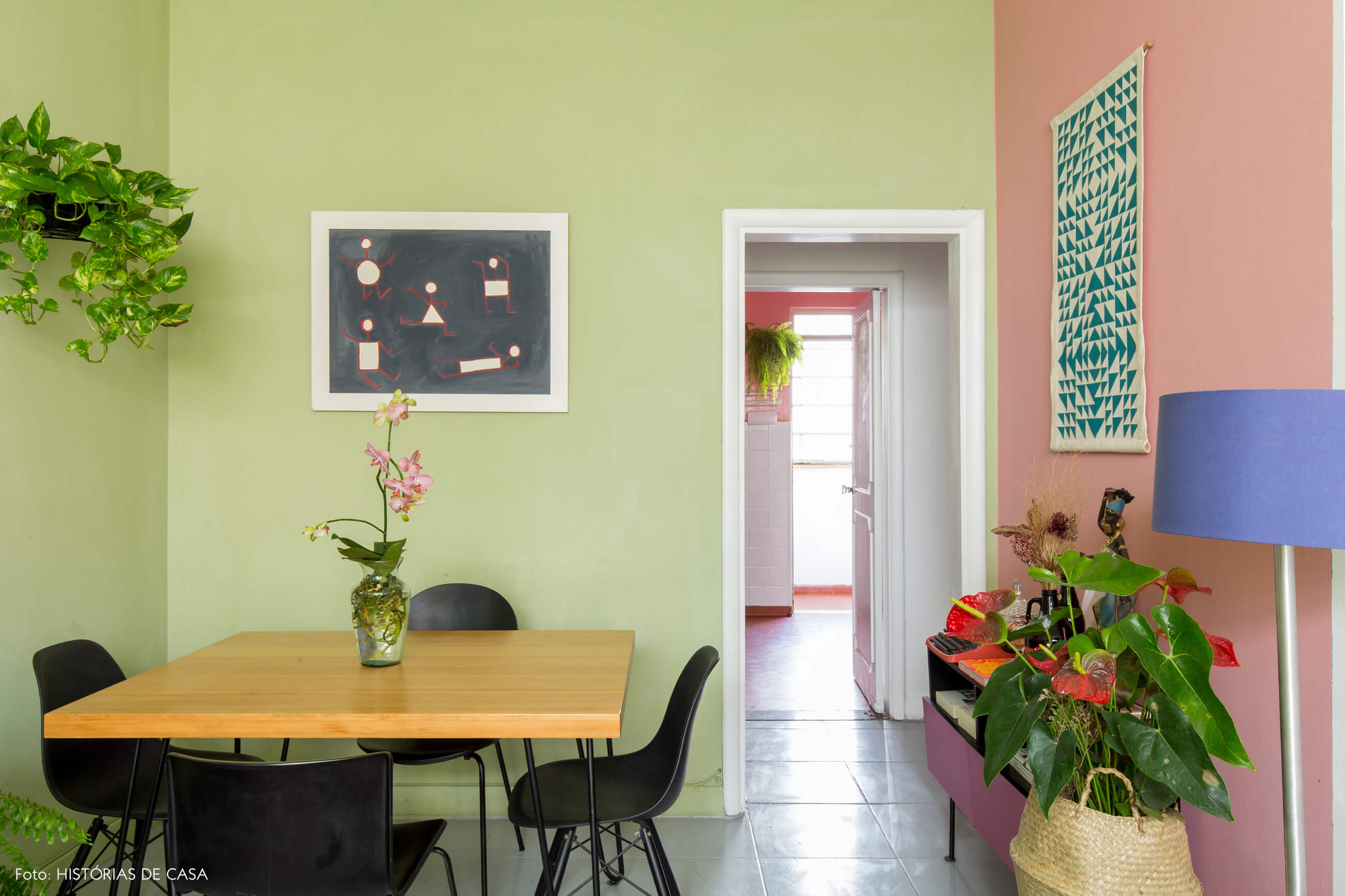 sala-jantar-mesa-madeira-cadeiras-pretas-cesto-palha-parede-verde-e-rosa-plantas-pinturas