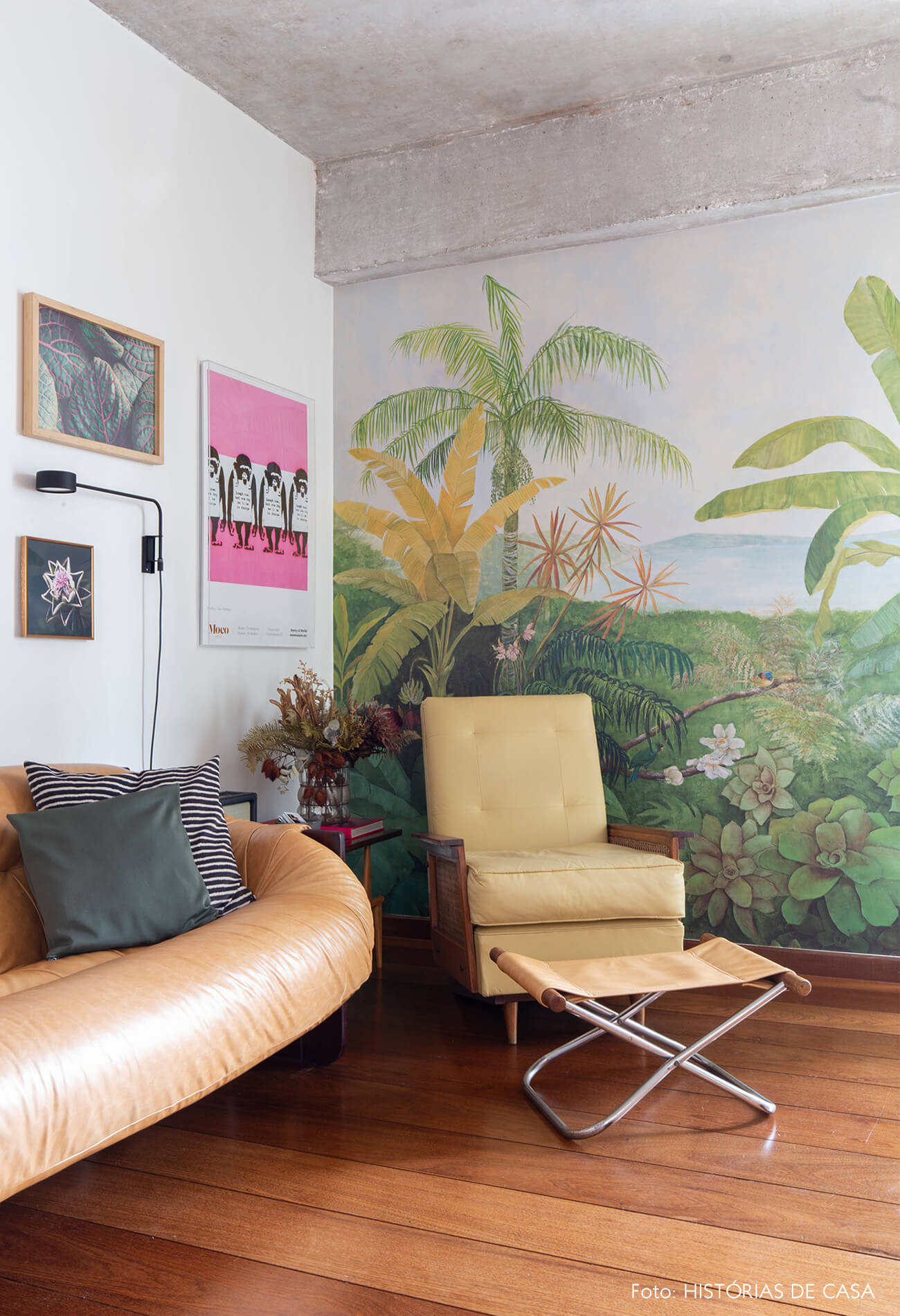 decoração sala com papel de parede de folhas e sofá de couro caramelo