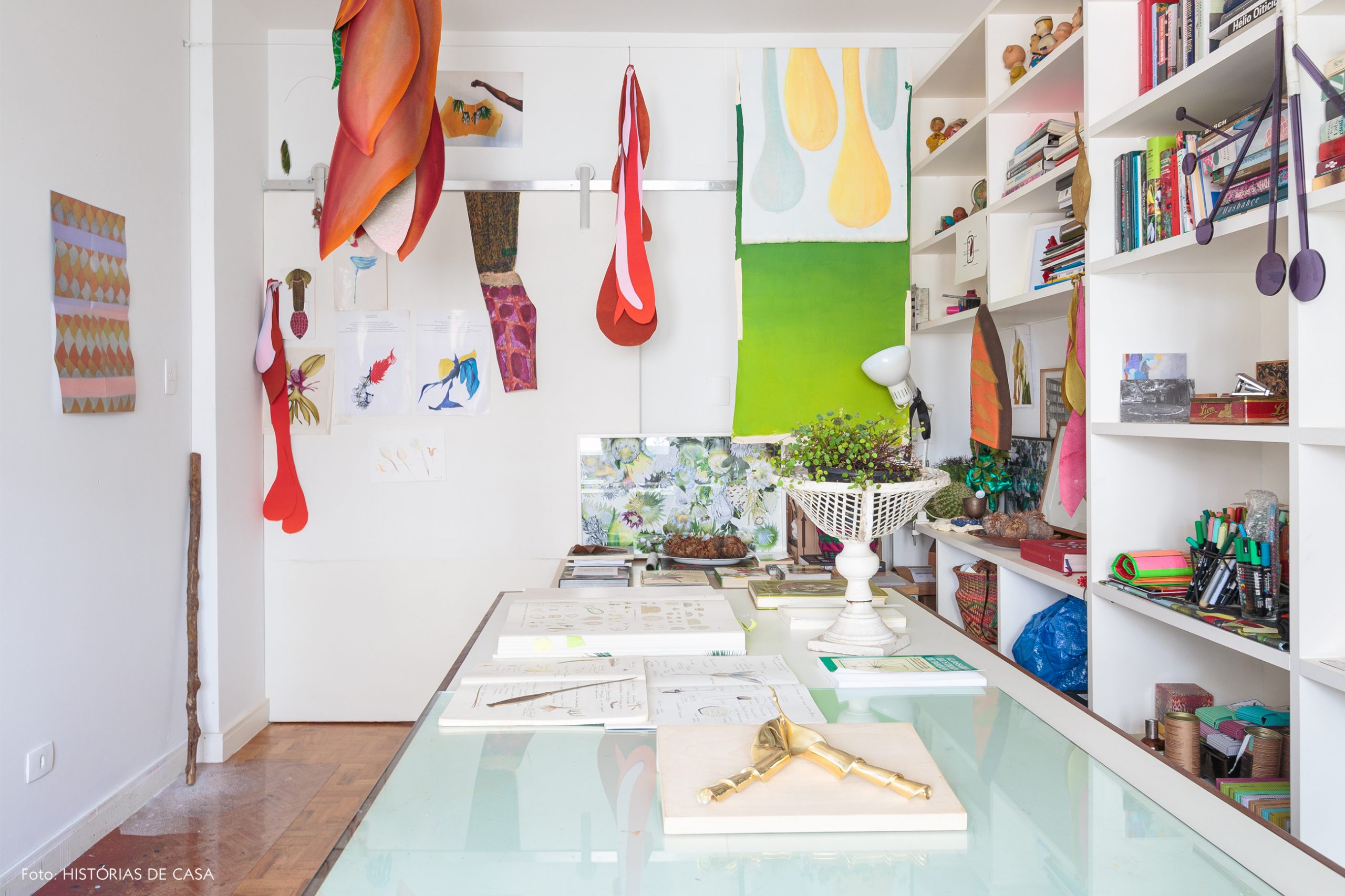 decoração atelie com obras de arte e estante branca