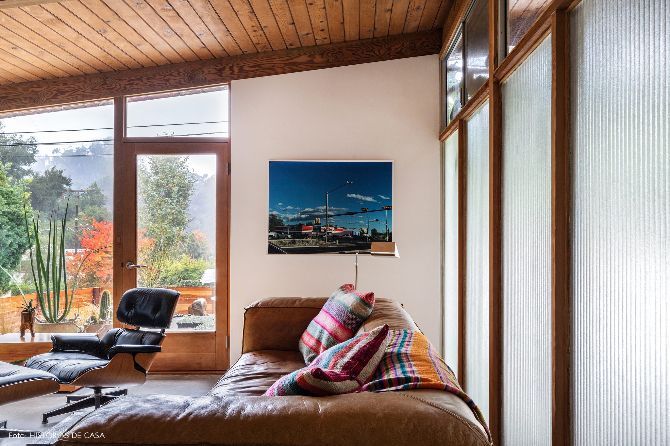 decoração casa sala com parede de vidro estrutura de madeira e sofá e poltrona de couro