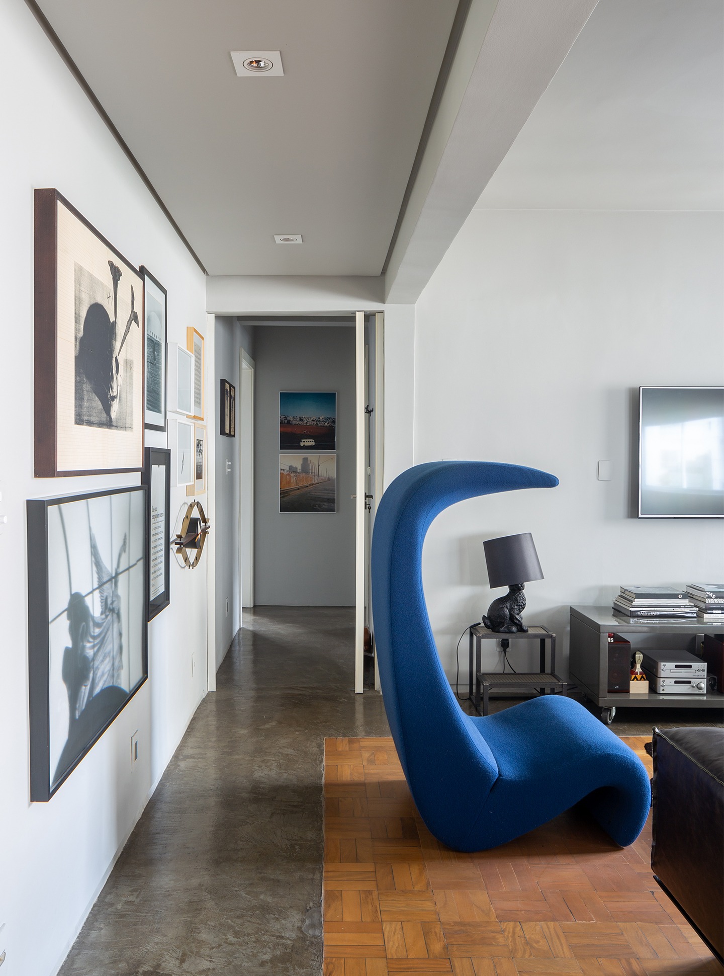 decoração sala tv com poltrona curva azul e abajur cachorro preto