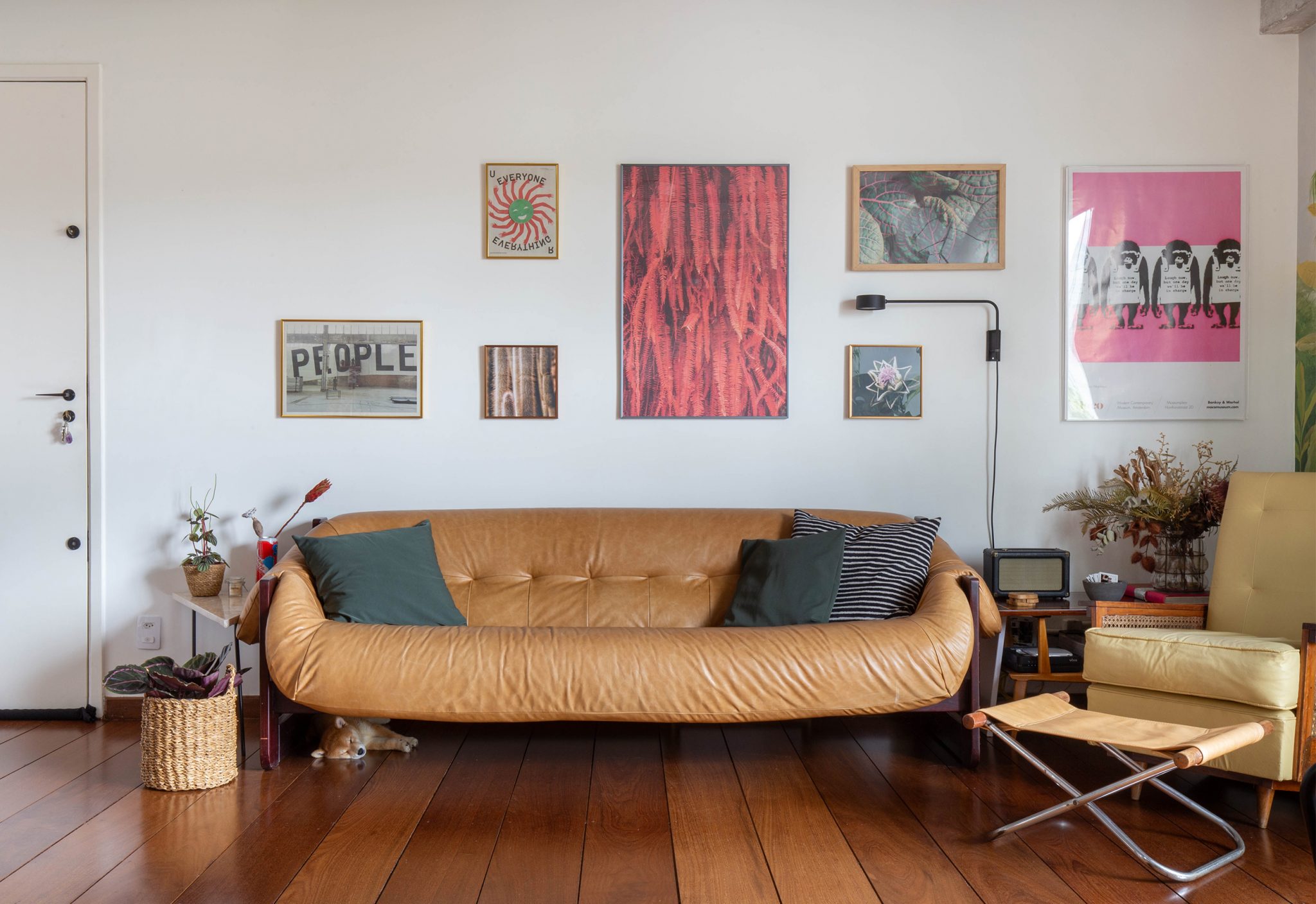 decoração sala com sofá de couro cesto de palha e quadros na parede