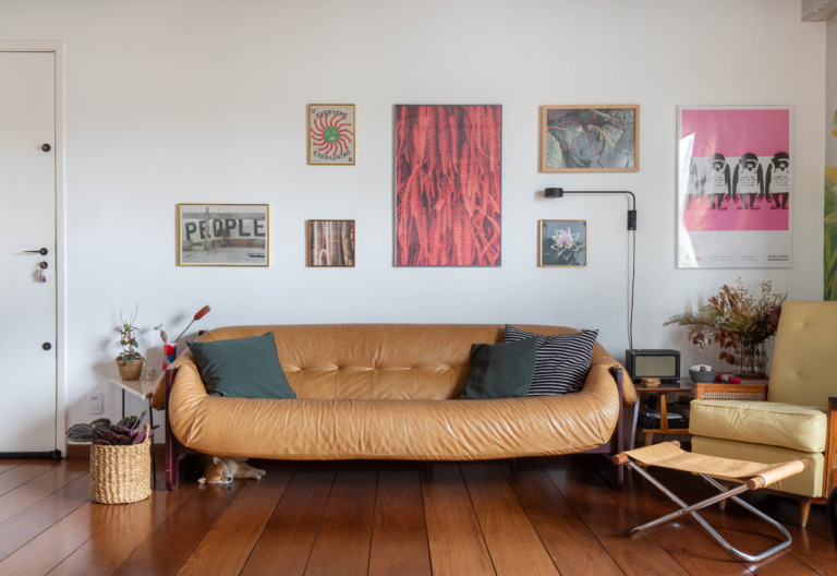 decoração sala com sofá de couro cesto de palha e quadros na parede