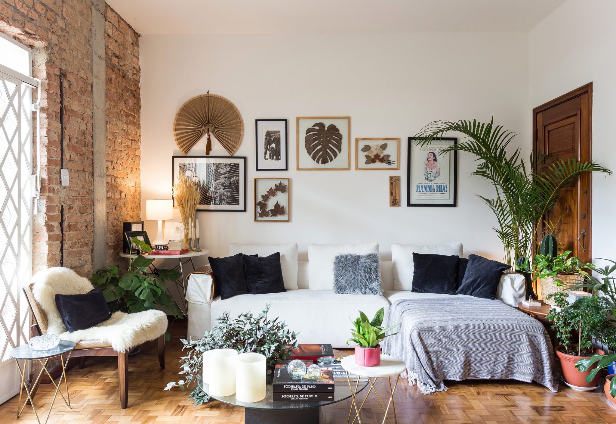 decoração sala com parede de tijolos muitas plantas e sofá branco