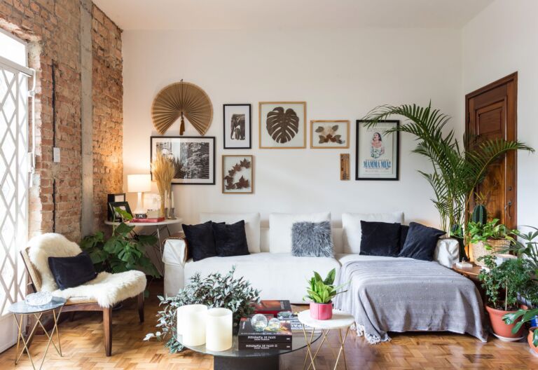 decoração sala com parede de tijolos muitas plantas e sofá branco