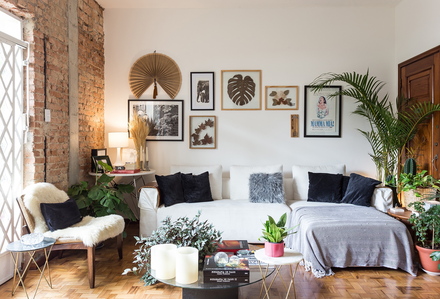 decoração sala com parede de tijolos muitas plantas e sofá branco