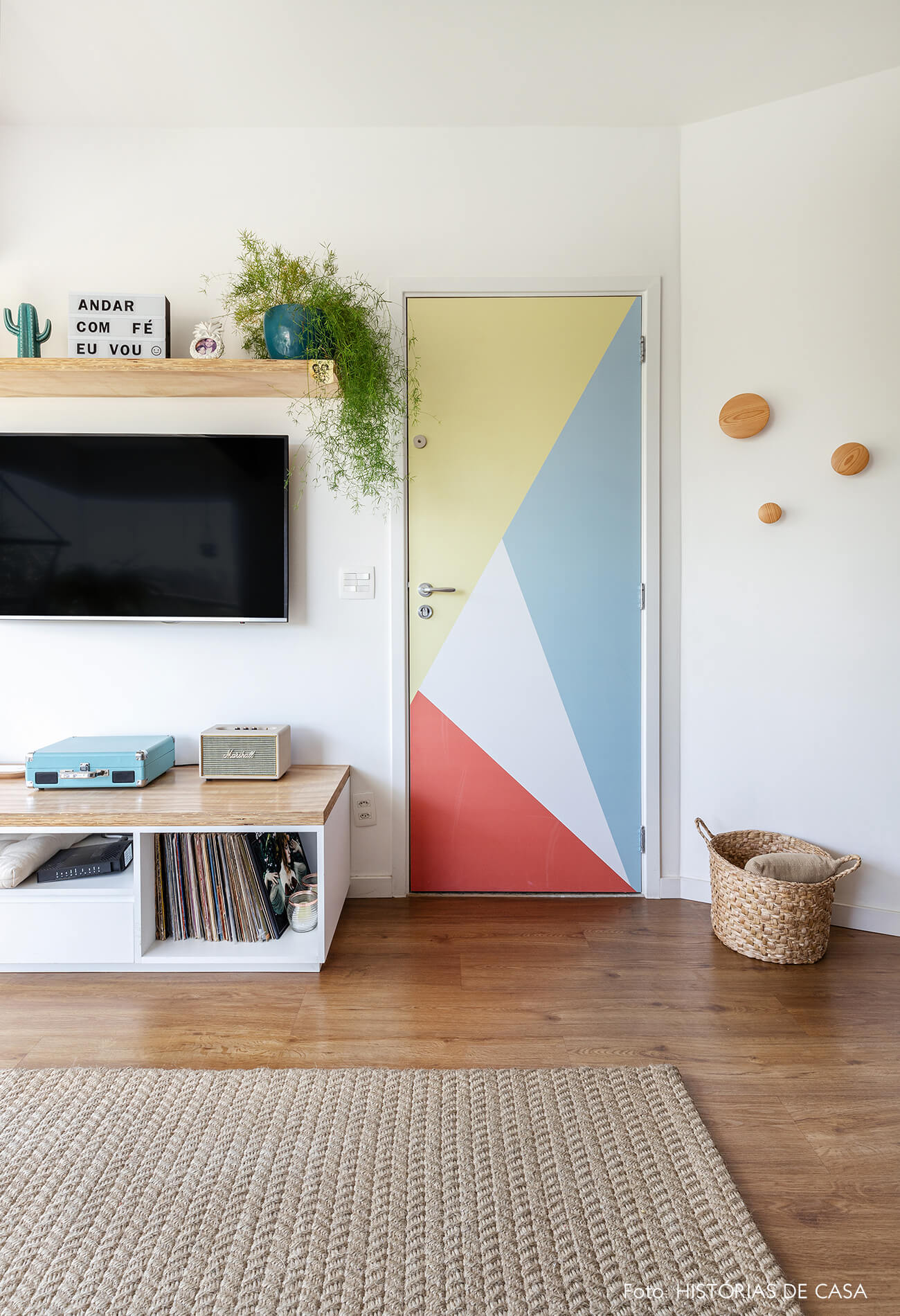 decoração sala com prateleiras de madeira e adesivo geometrico em porta