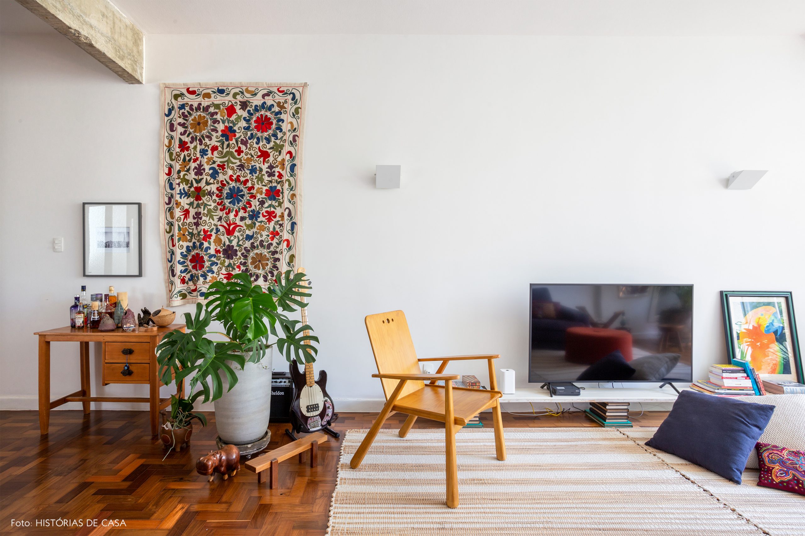 decoração sala com painel de tecido na parede, cadeira de madeira e almofadas no chão