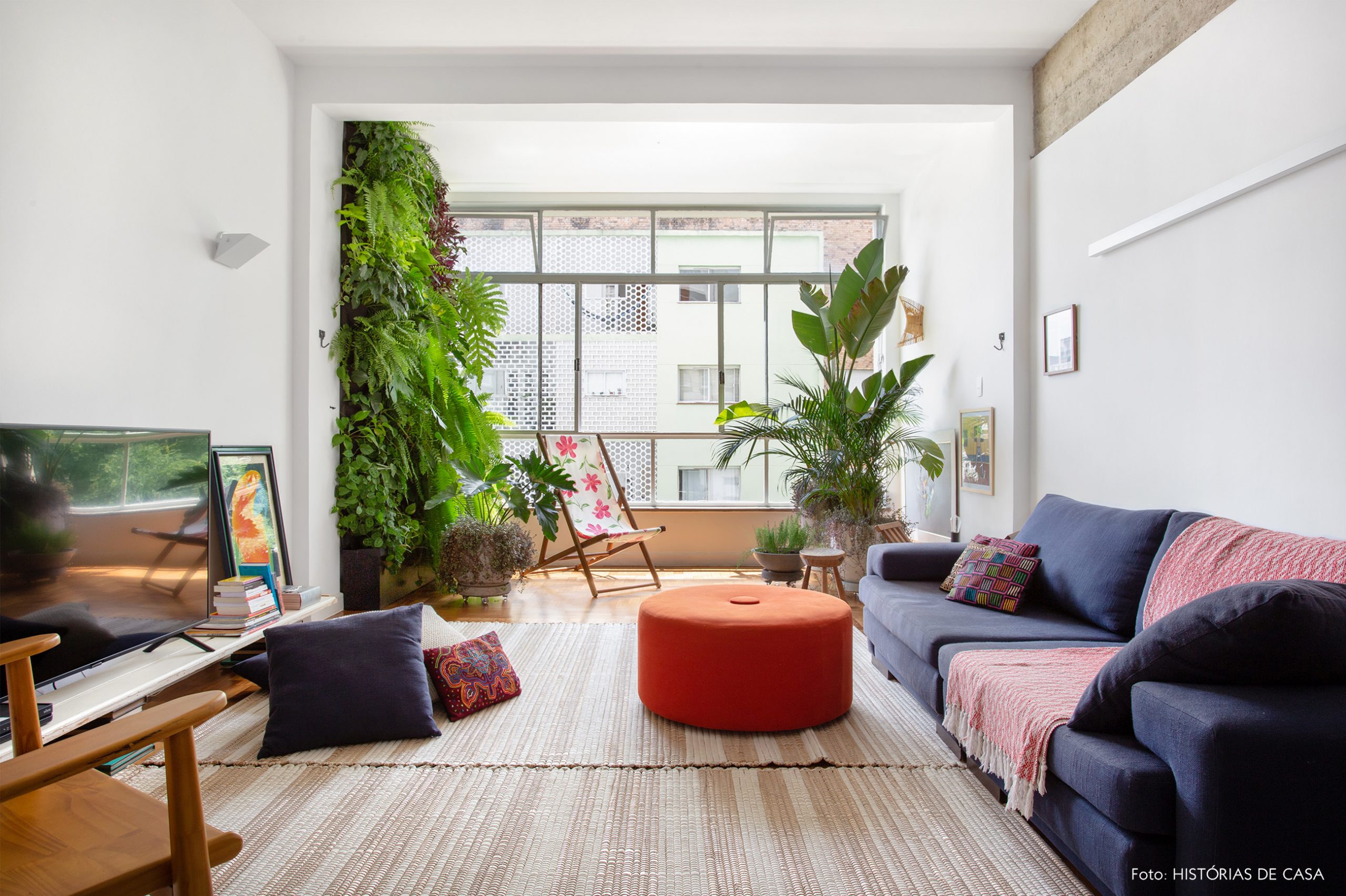 decoração sala com muitas plantas, pufes coloridos e cadeira de madeira e tecido