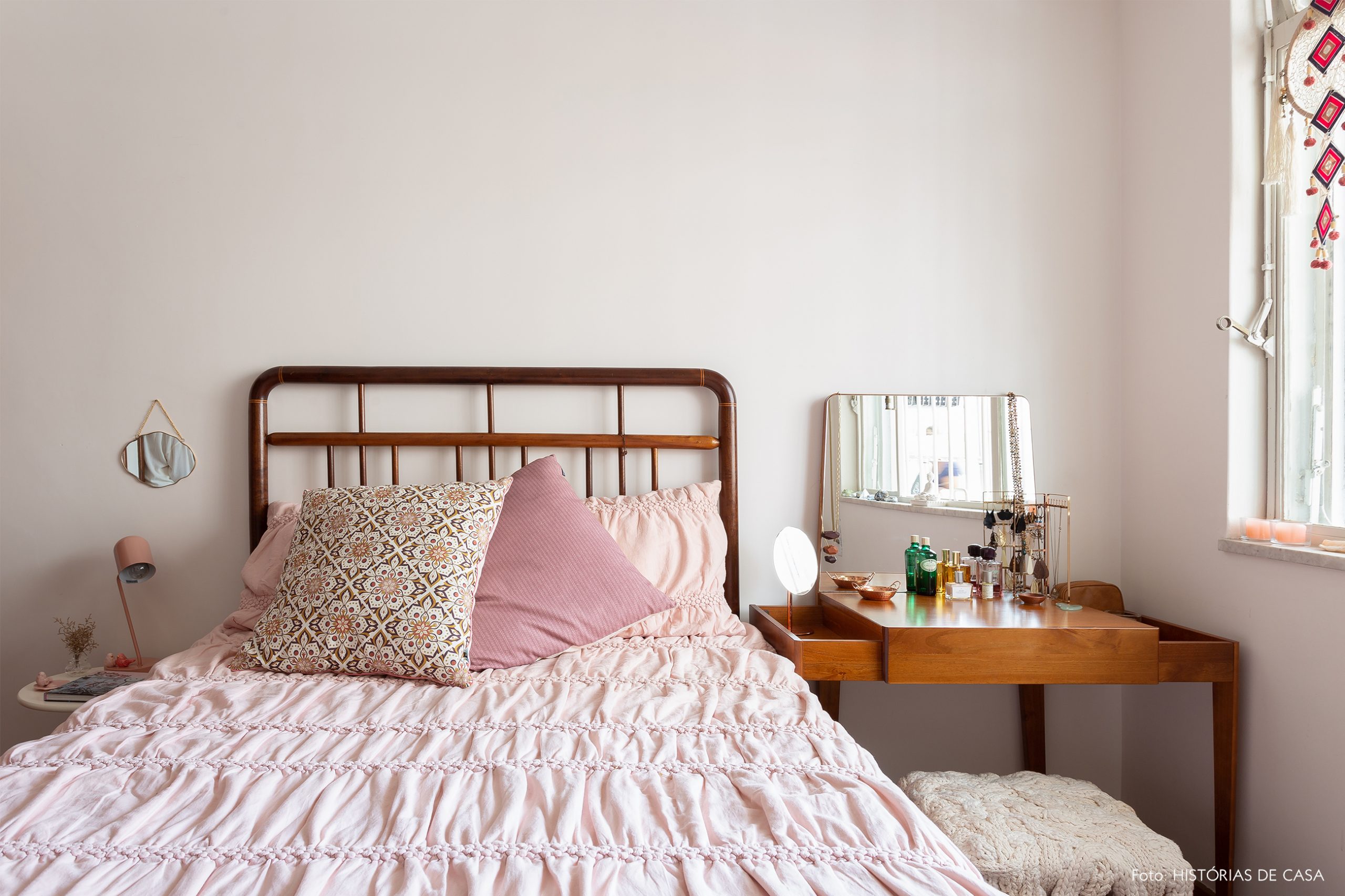 decoração quarto com parede rosa claro e cama de madeira escura