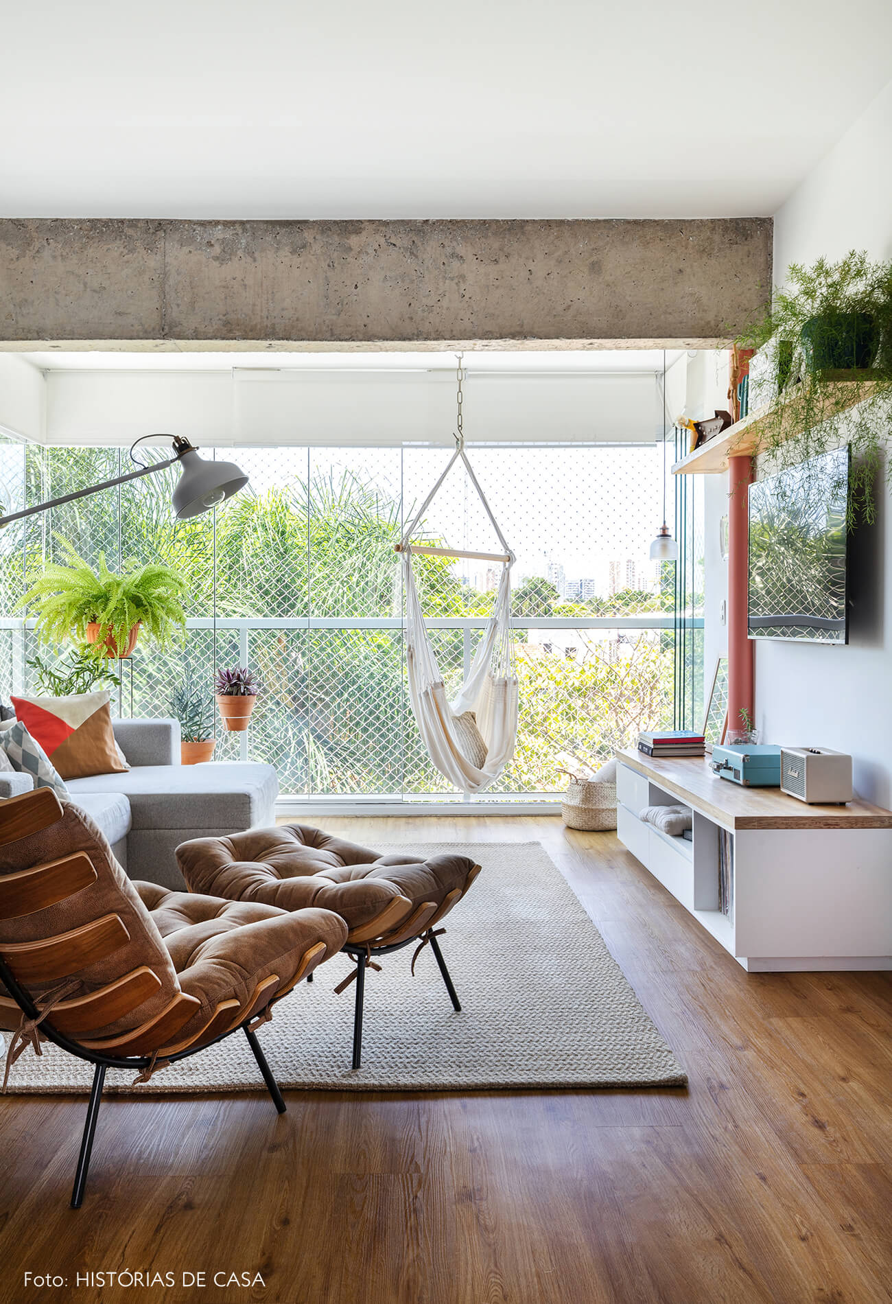 decoração sala com poltrona costela, muitas plantas e poltrona rede