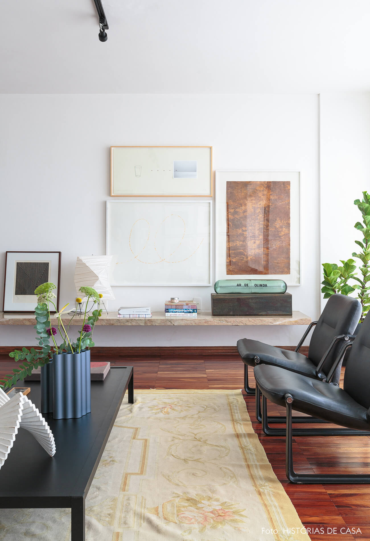 decoração sala com poltronas e mesa de centro pretas e obras de arte