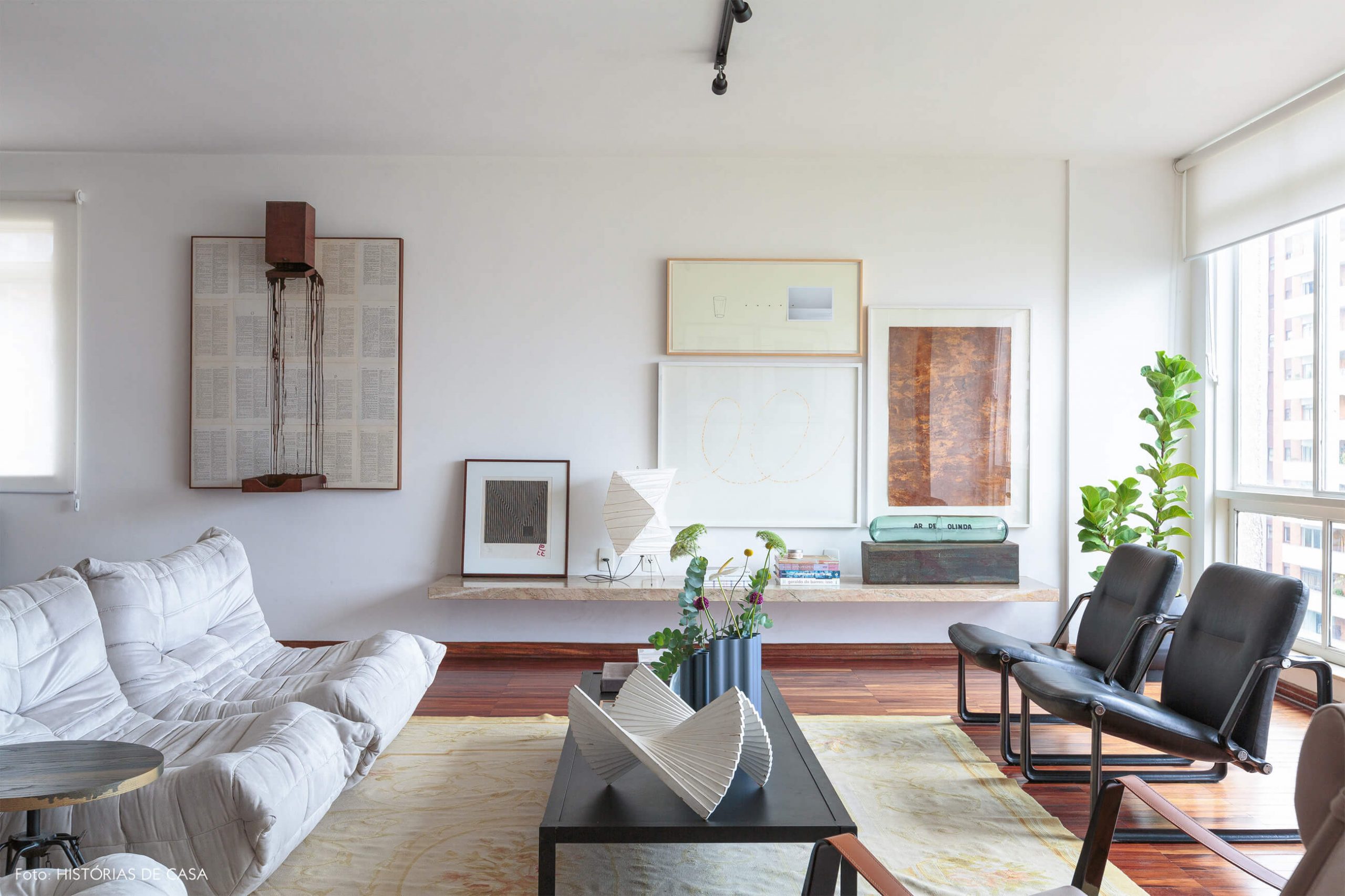 decoração sala bem iluminada com obras de arte e sofá branco