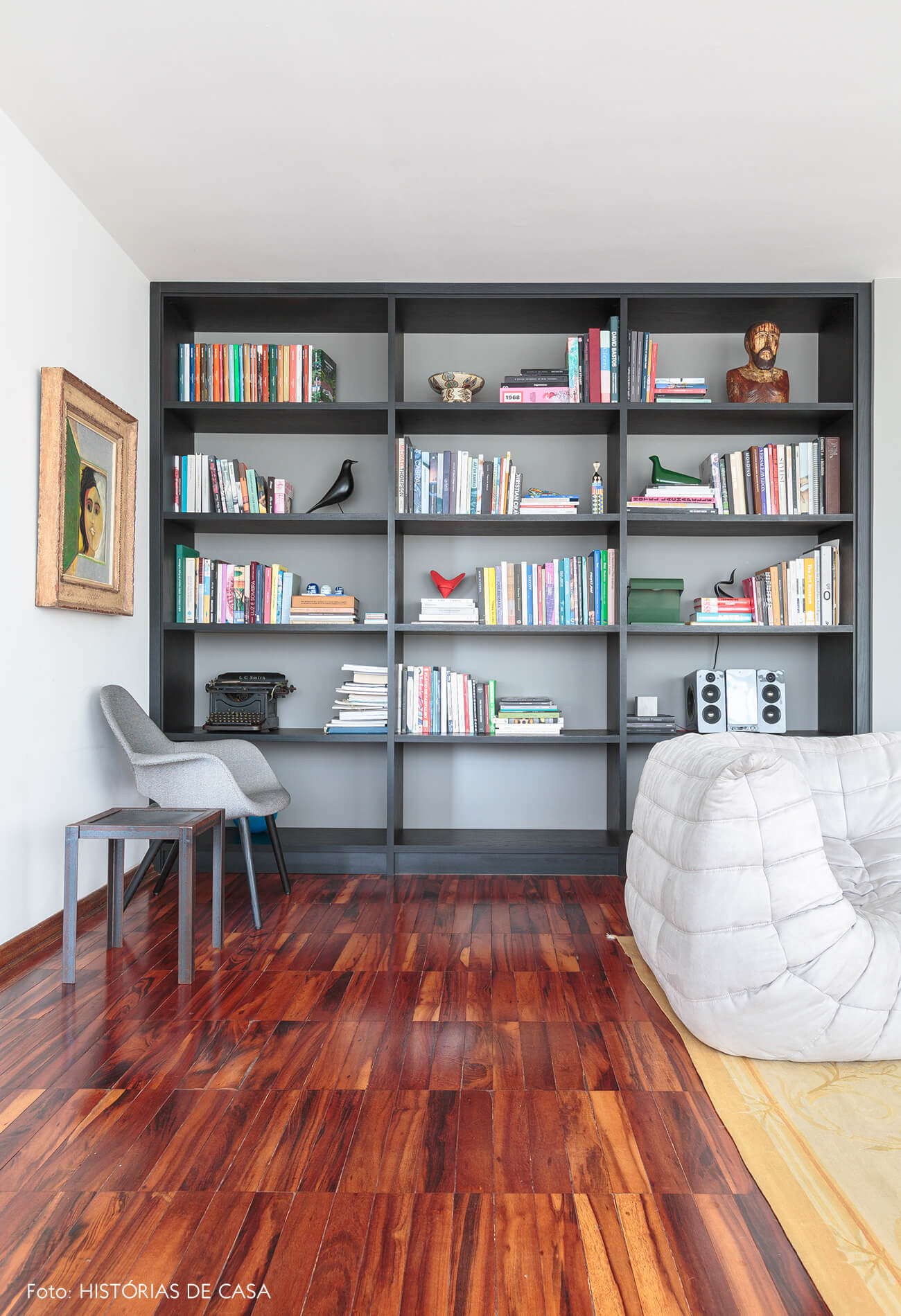 decoração sala com piso de madeira sofá branco e estante preta