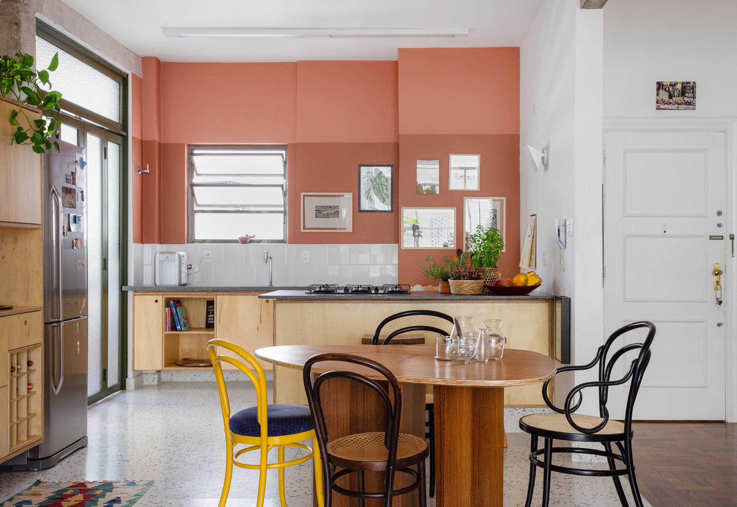 decoração cozinha com parede terrosa, porta serralheria, e cadeira thone