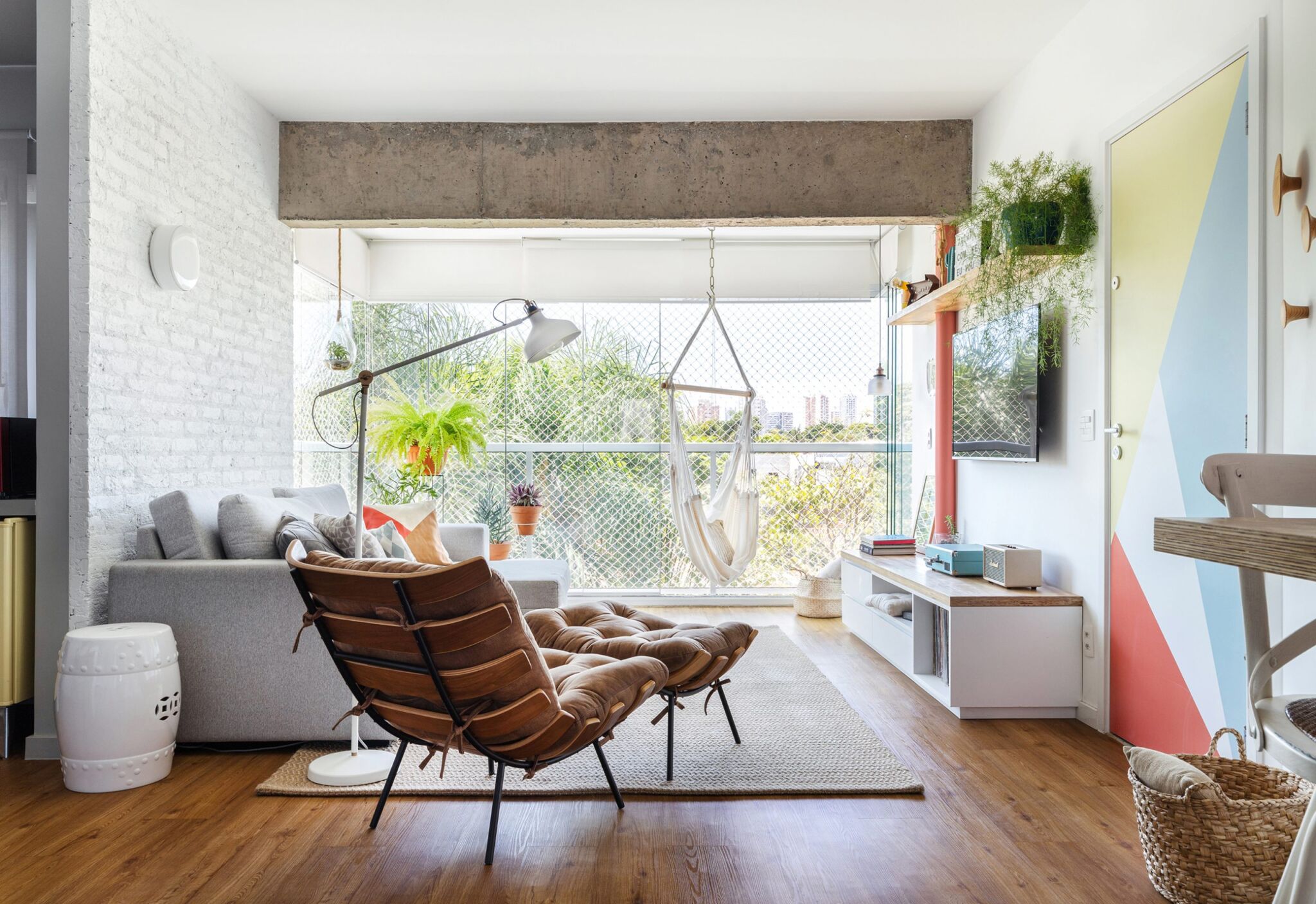 decoração sala com parede de tijolos brancos, poltrona costela e porta com adesivo geométrico