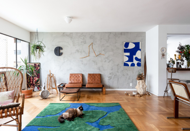 decoração sala de parede de cimento queimado poltronas de couro e tapete verde e azul