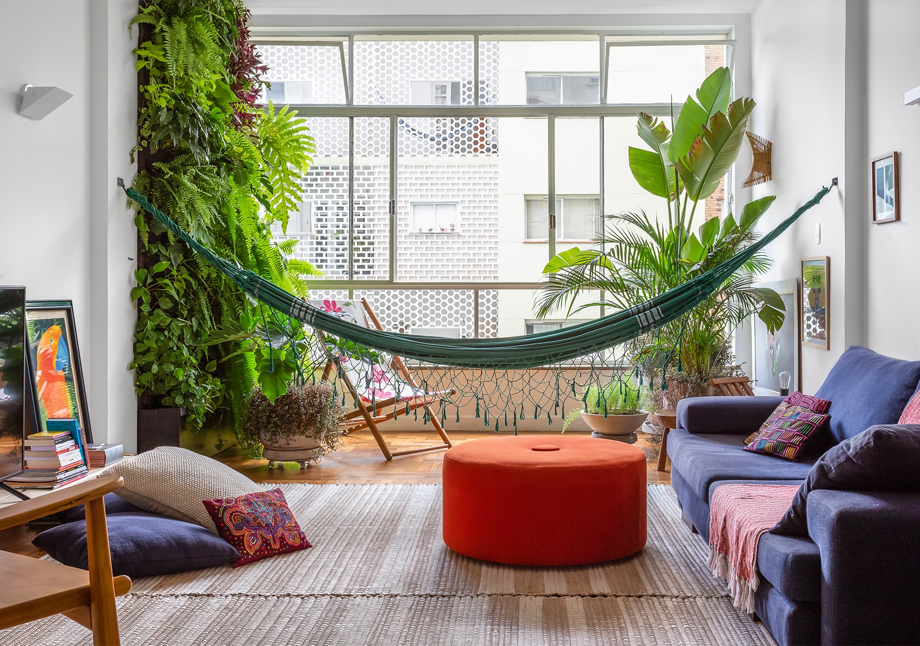 decoração sala com muitas plantas, rede e pufe colorido