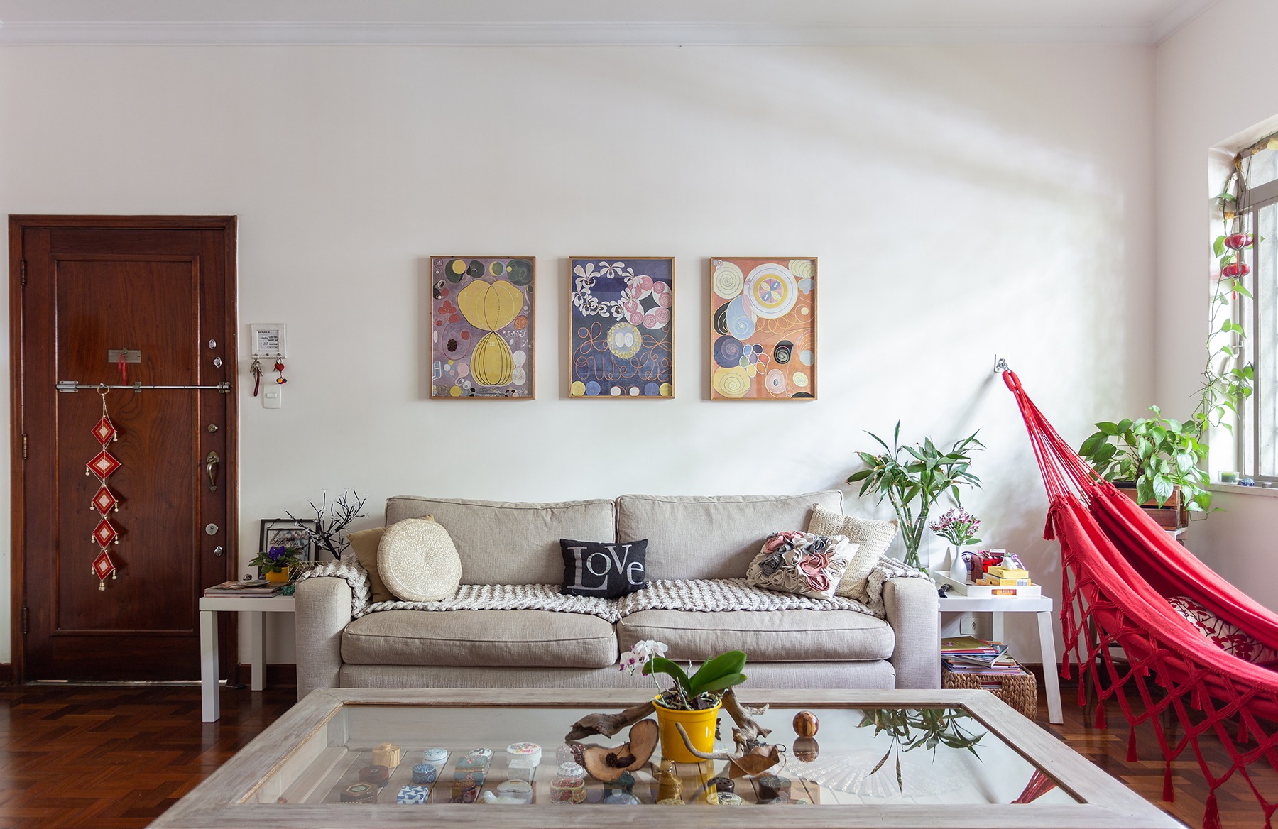 decoração sala com sofá cinza rede vermelha e mesa de madeira e vidro