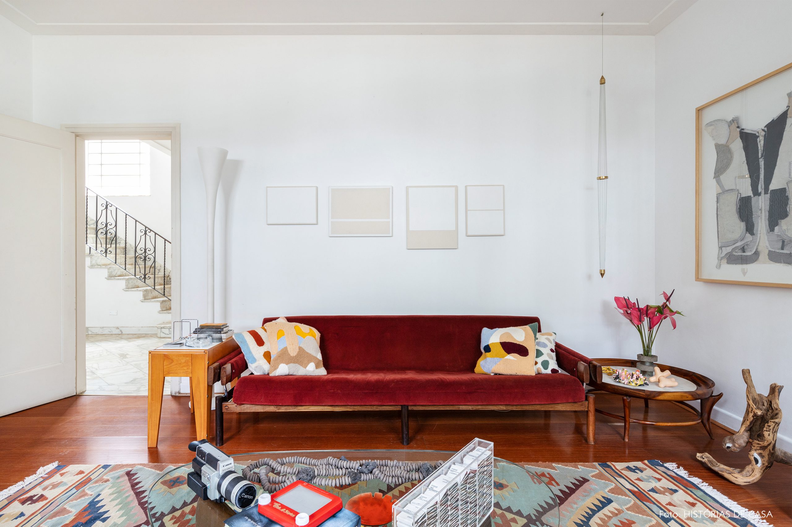 decoração sala com sofá vermelho, tapete estampado e mesa de madeira