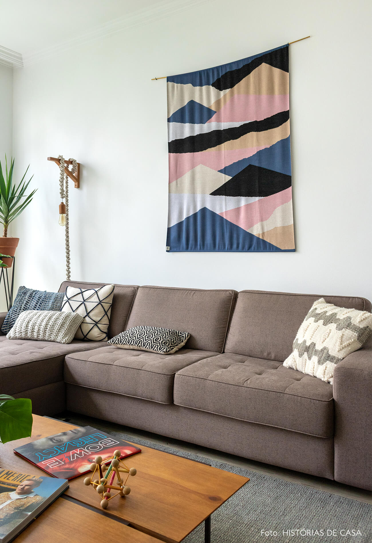 decoração sala com sofá cinza, tapeçaria na parede e plantas