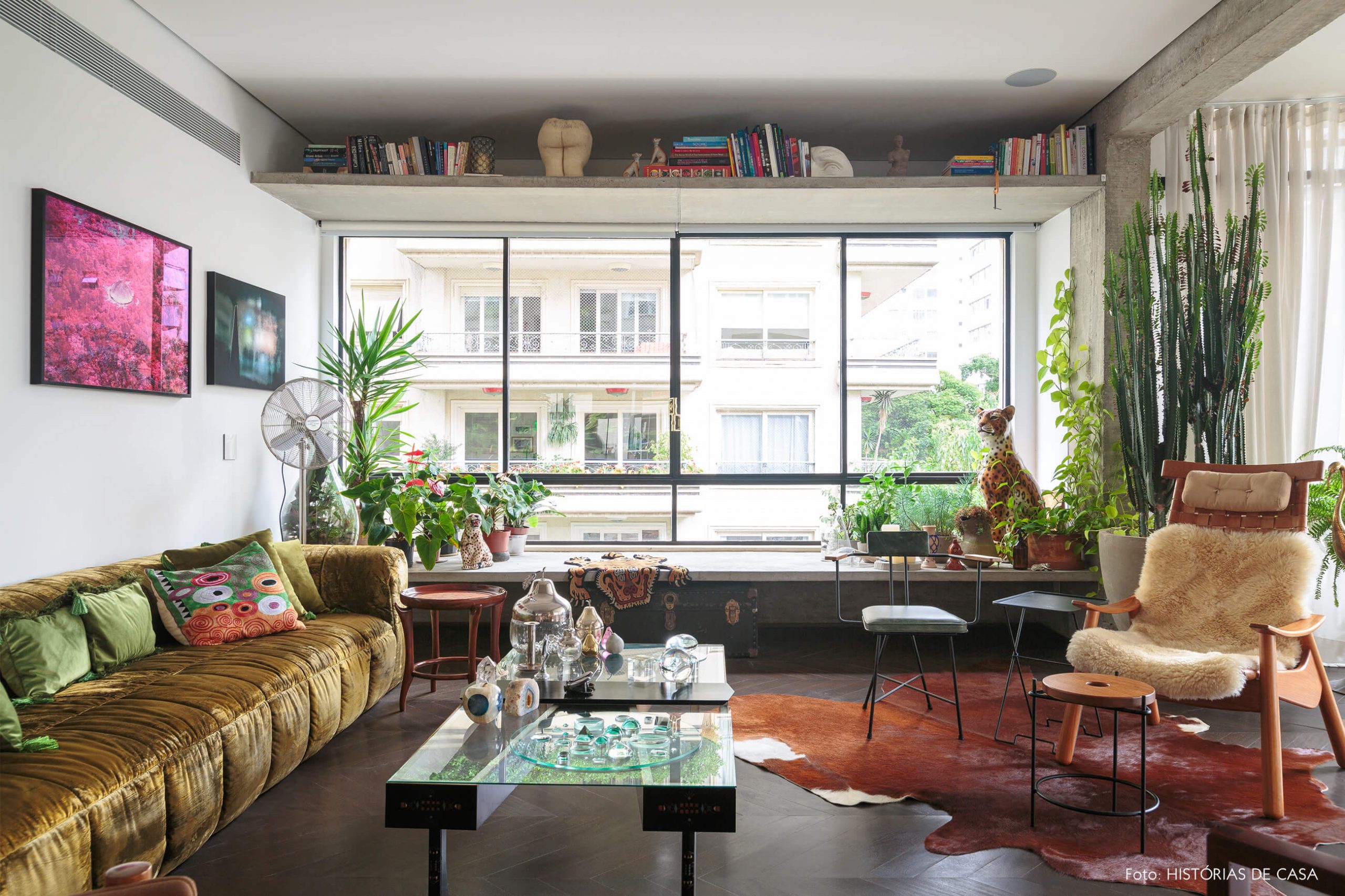 decoração ap sala com sofá de veludo verde e banco de concreto com muitas plantas