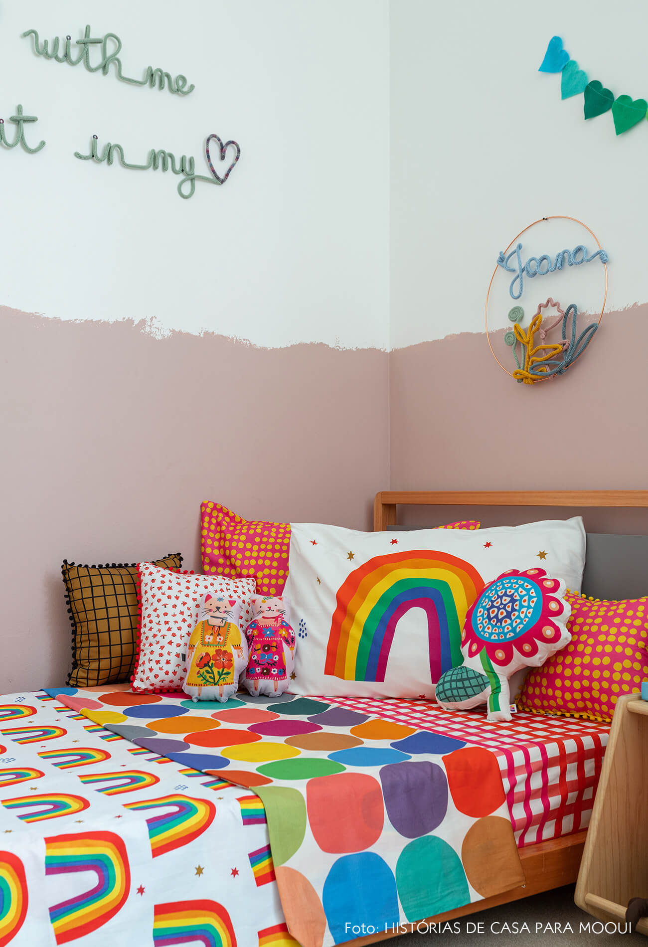 Quarto de menina com parede pintada até metade e roupa de cama de arco-íris