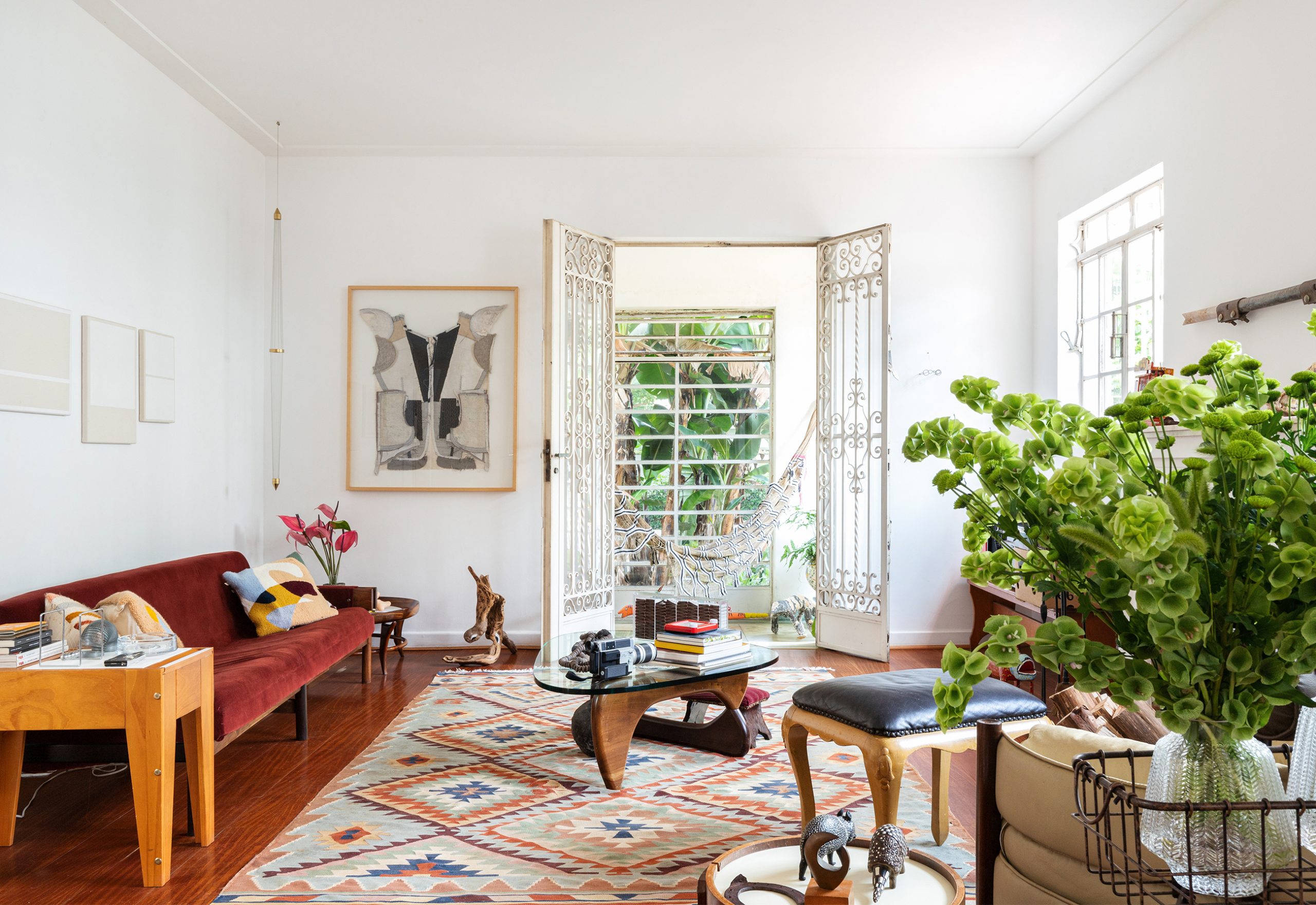 decoração sala com sofá vermelho, tapete estampado e mesa de madeira