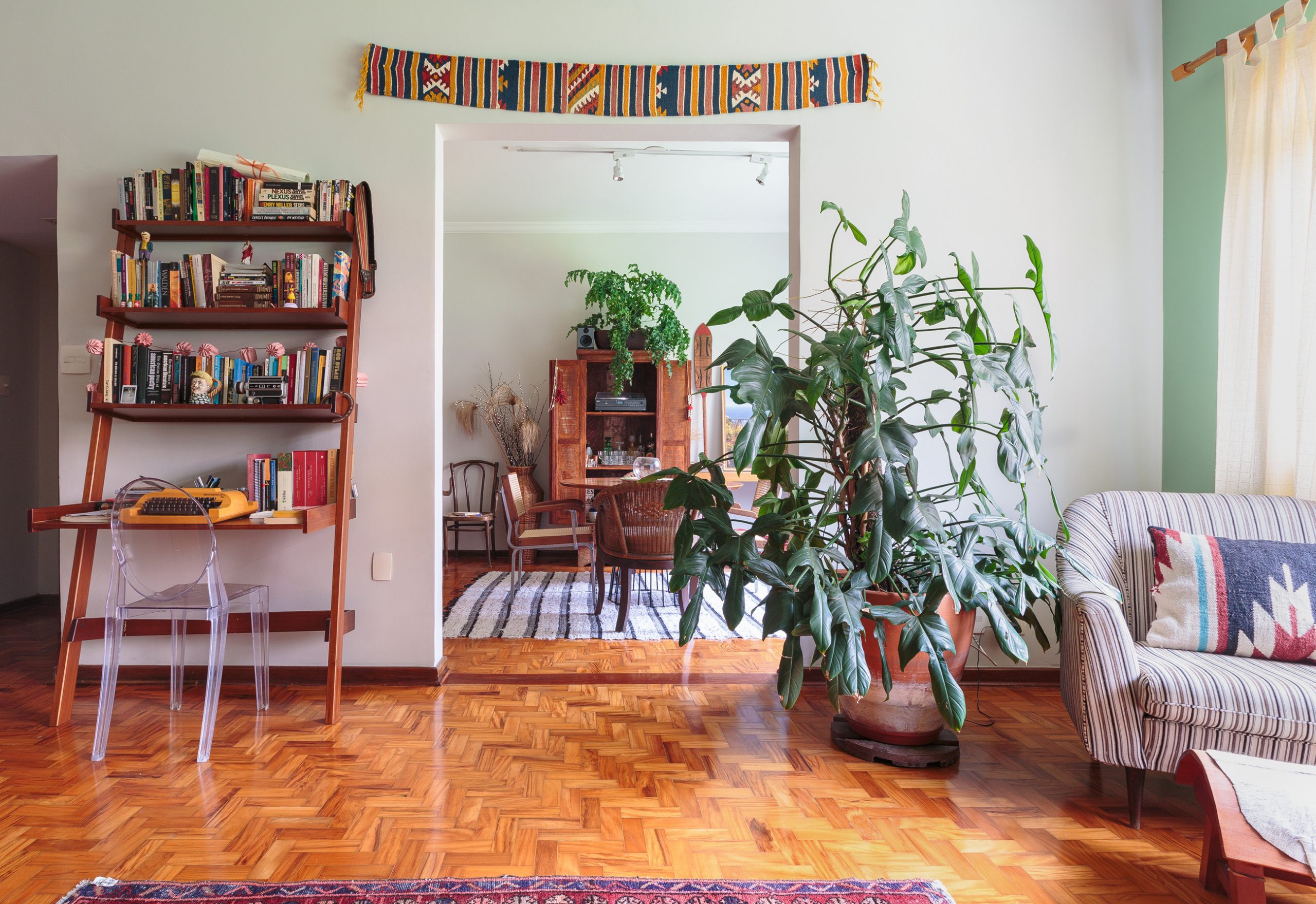 decoração sala com plantas, cadeira ghost e estante de madeira