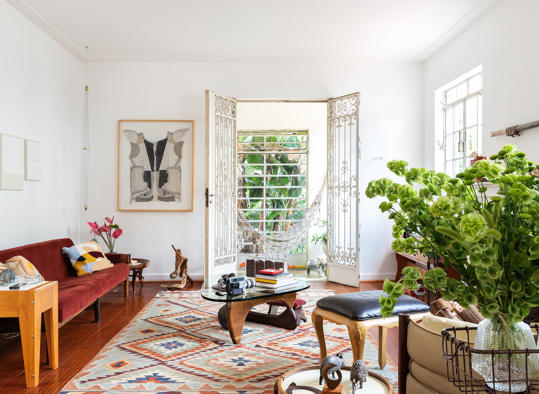decoração sala com sofá vermelho, tapete estampado e mesa de madeira