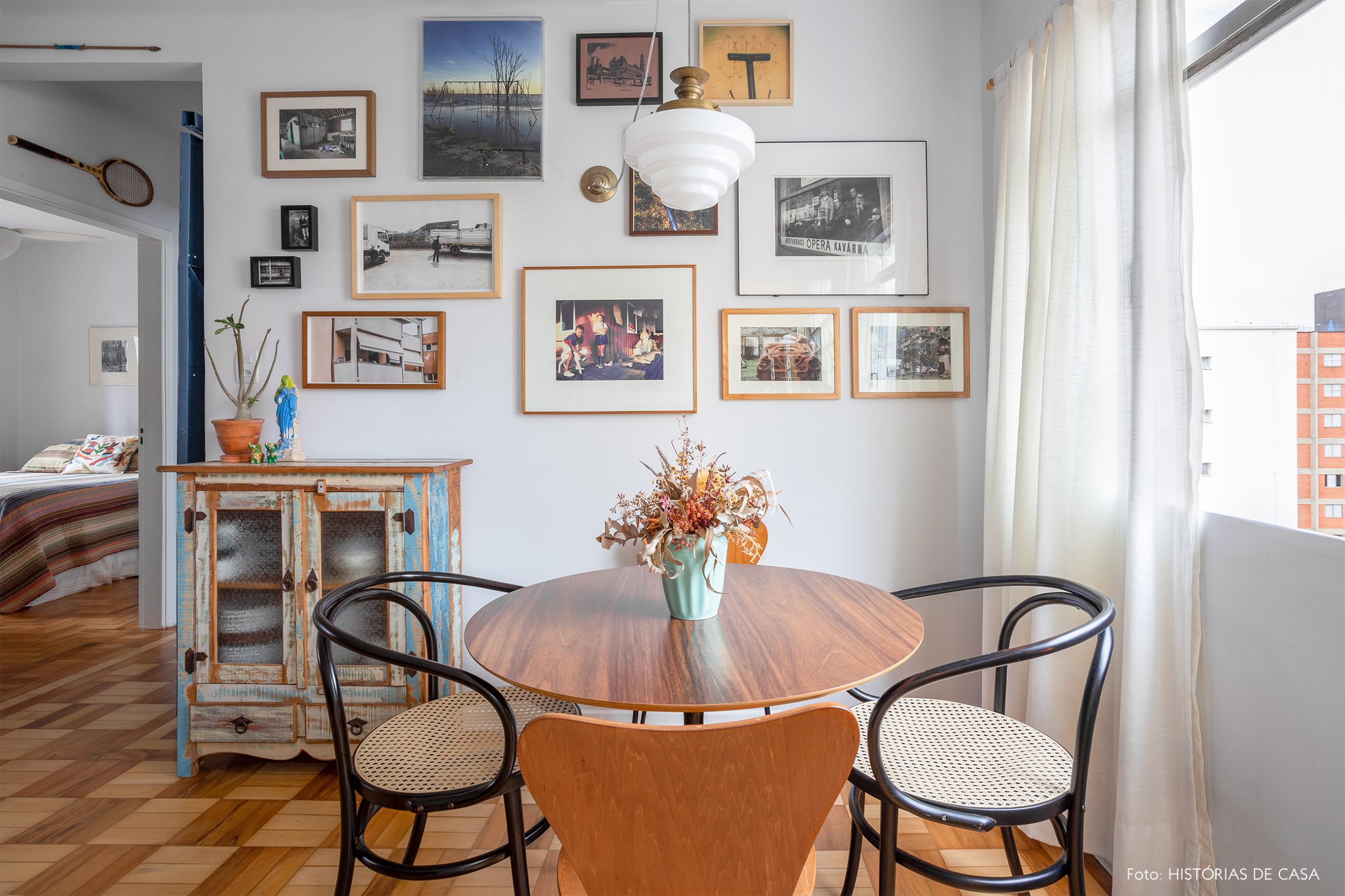 decoração sala jantar com mesa redonda de madeira e muitos quadros