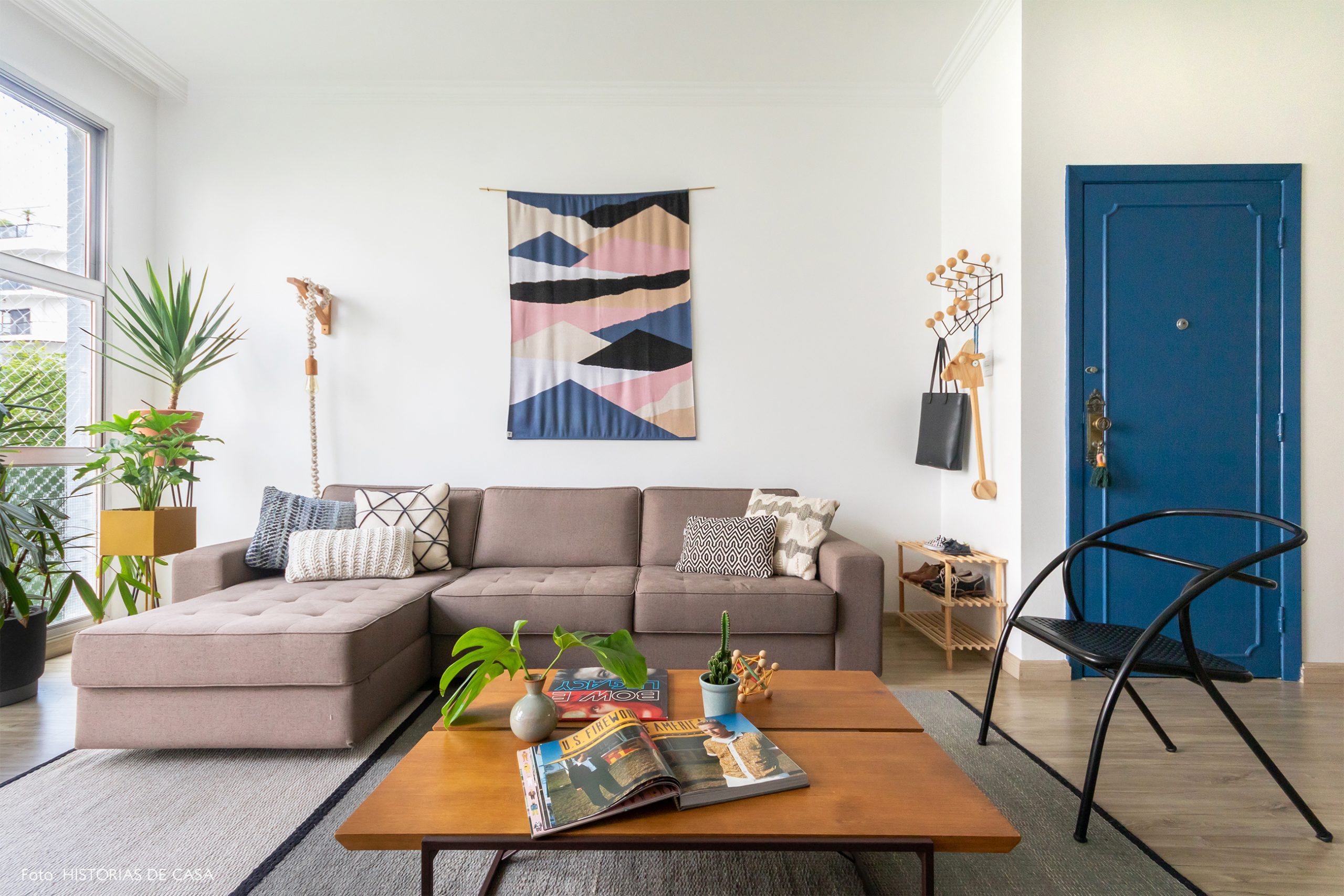 decoração sala com sofá cinza, mesa de madeira e tapeçaria na parede