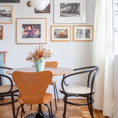 decoração sala jantar com muitos quadros e mesa redonda de madeira