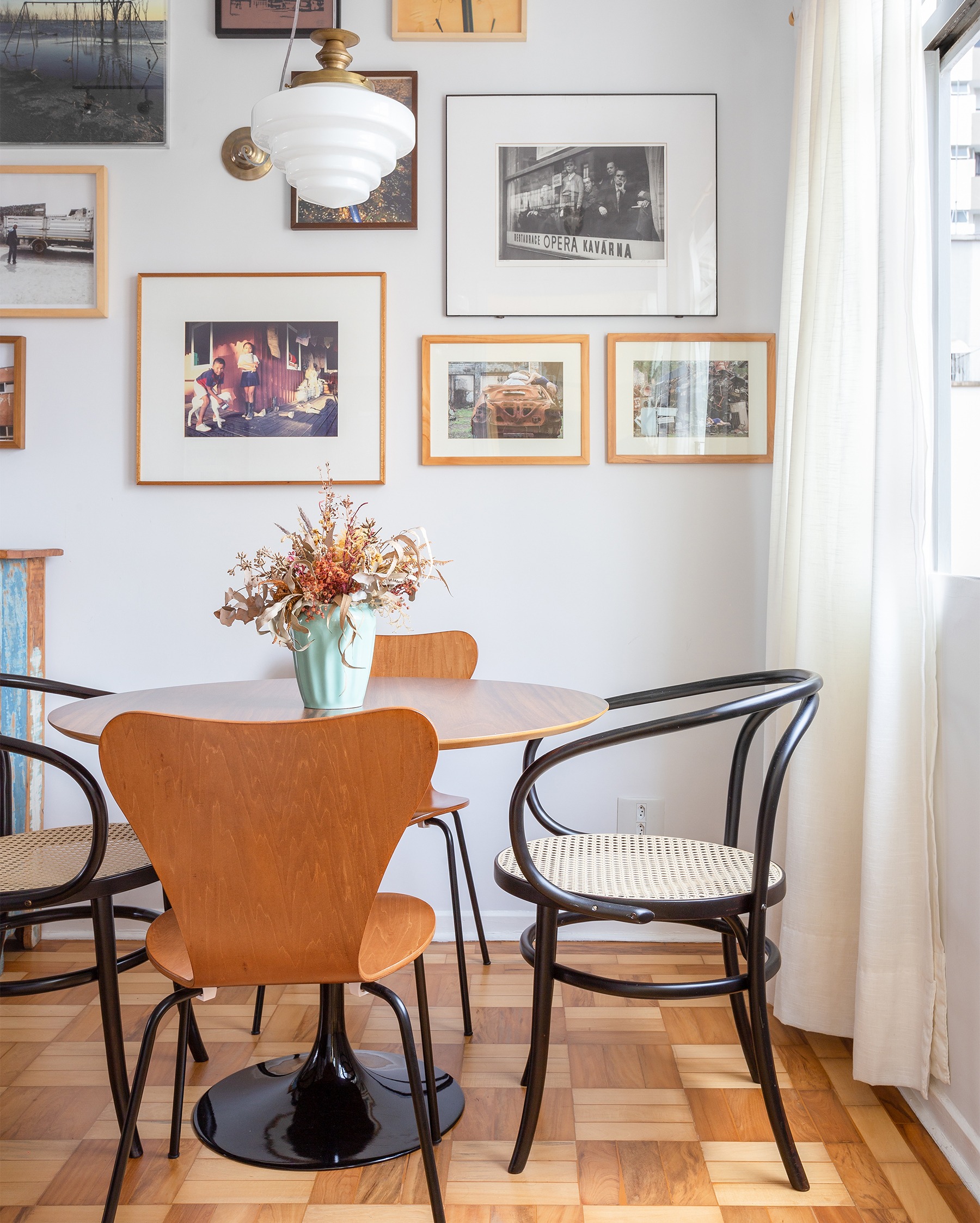 decoração sala jantar com muitos quadros e mesa redonda de madeira
