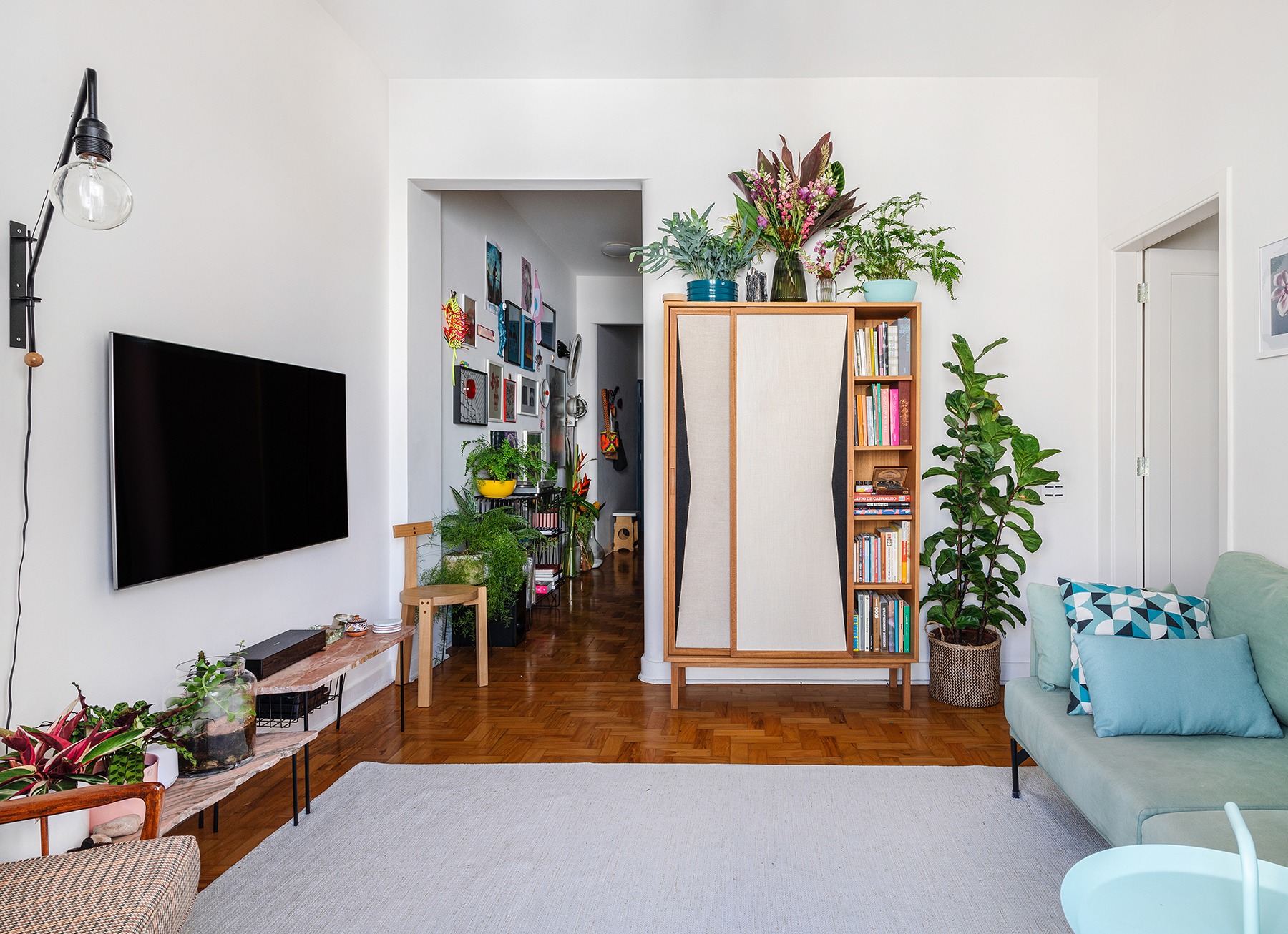 decoração sala com sofa azul muitas plantas banco girafa lina