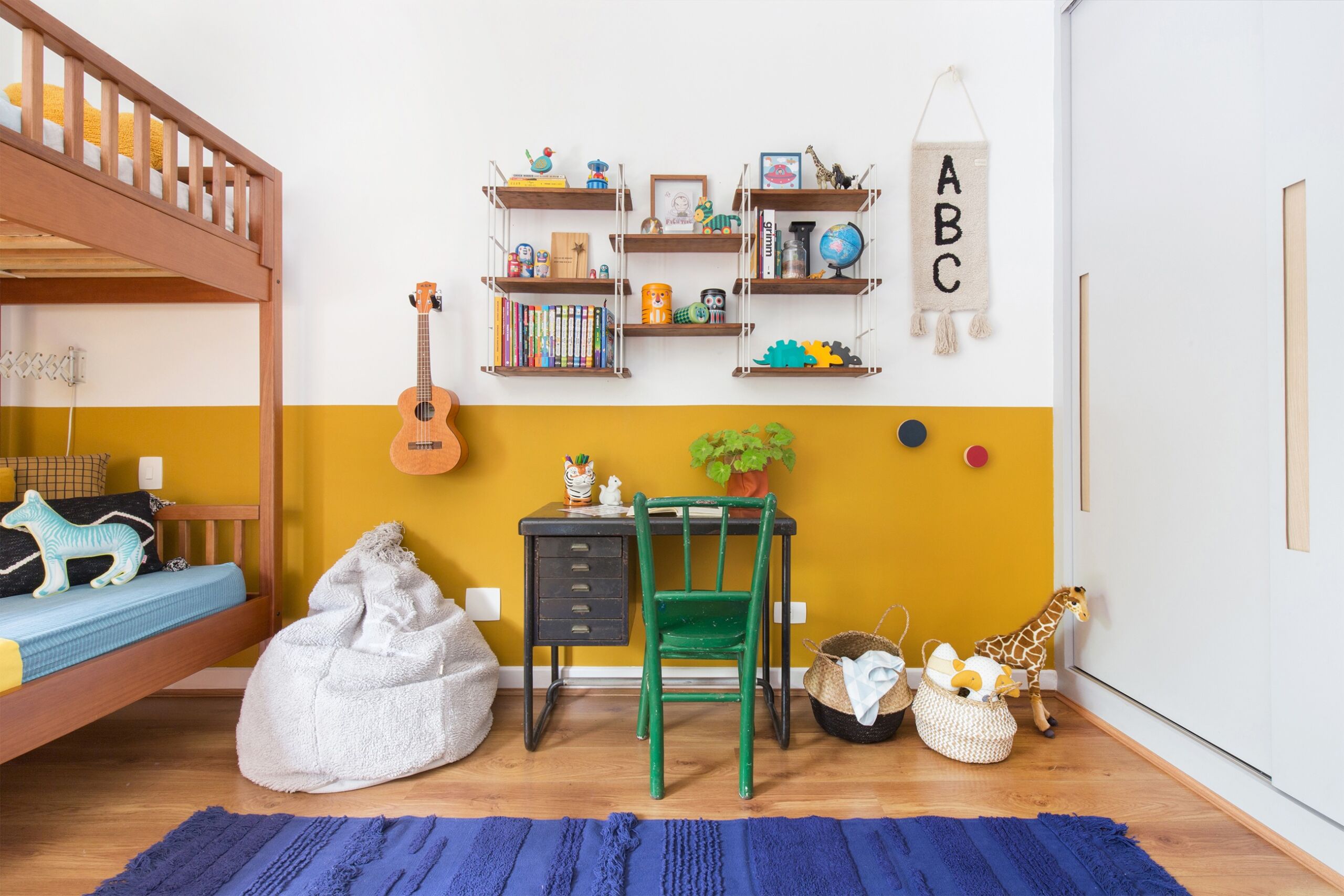 quarto infantil decoração pufe, tapete azul, meia parede amarela