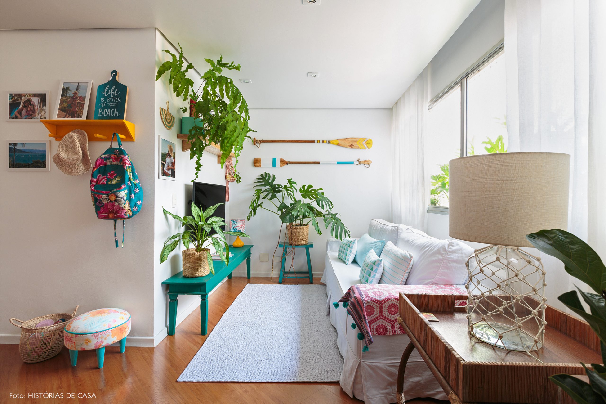 decoração praiana sala com muitas plantas, cestos e bancos azuis de madeira